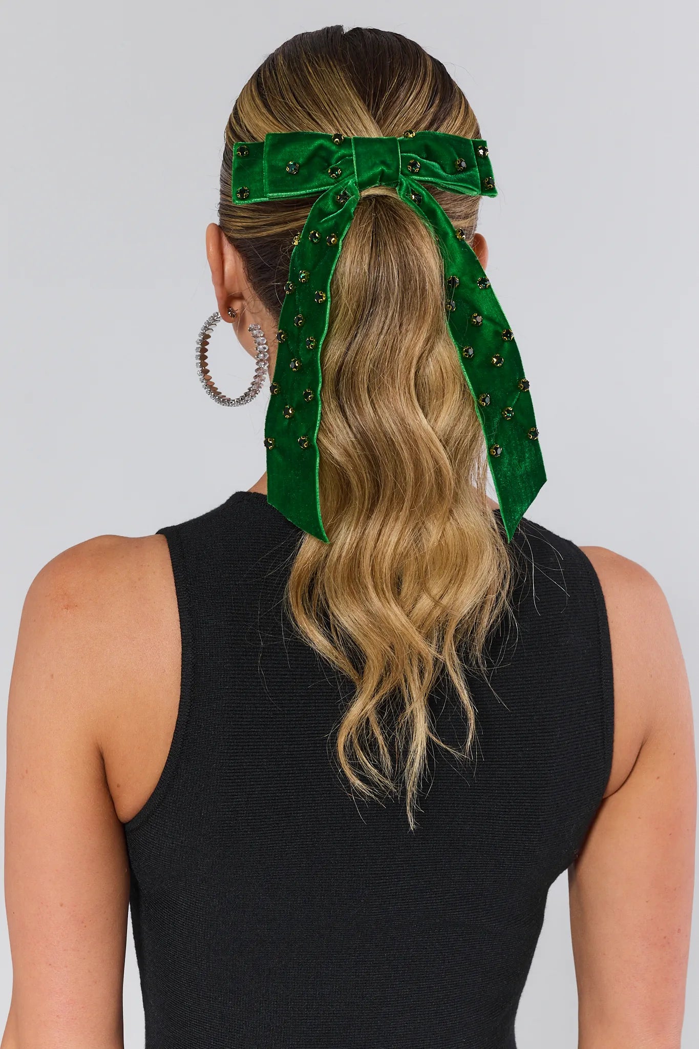 Person wearing a green hair bow with decorative elements on a plain background