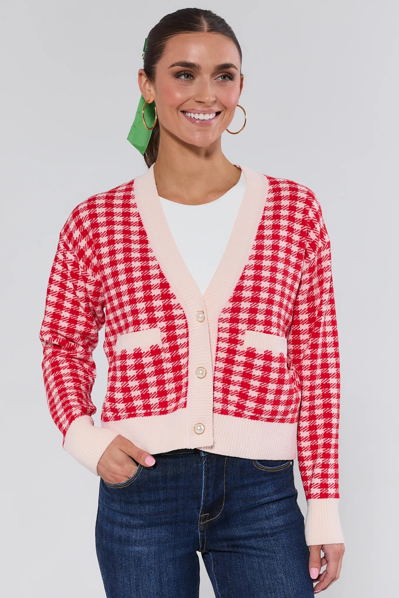 Woman wearing a red and white checkered cardigan with a plain background