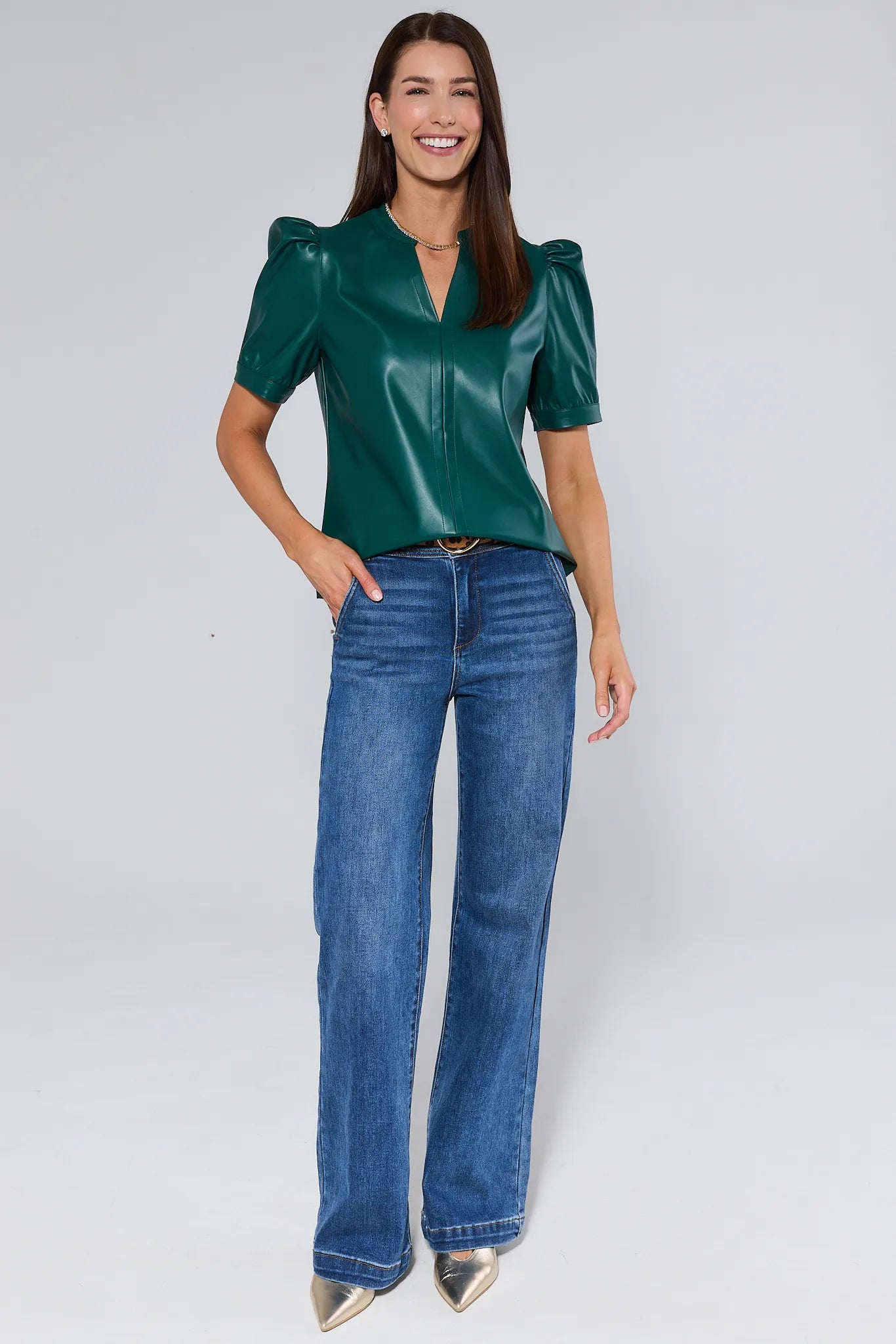 Woman wearing a green Ariana Top with puff sleeves against a plain background