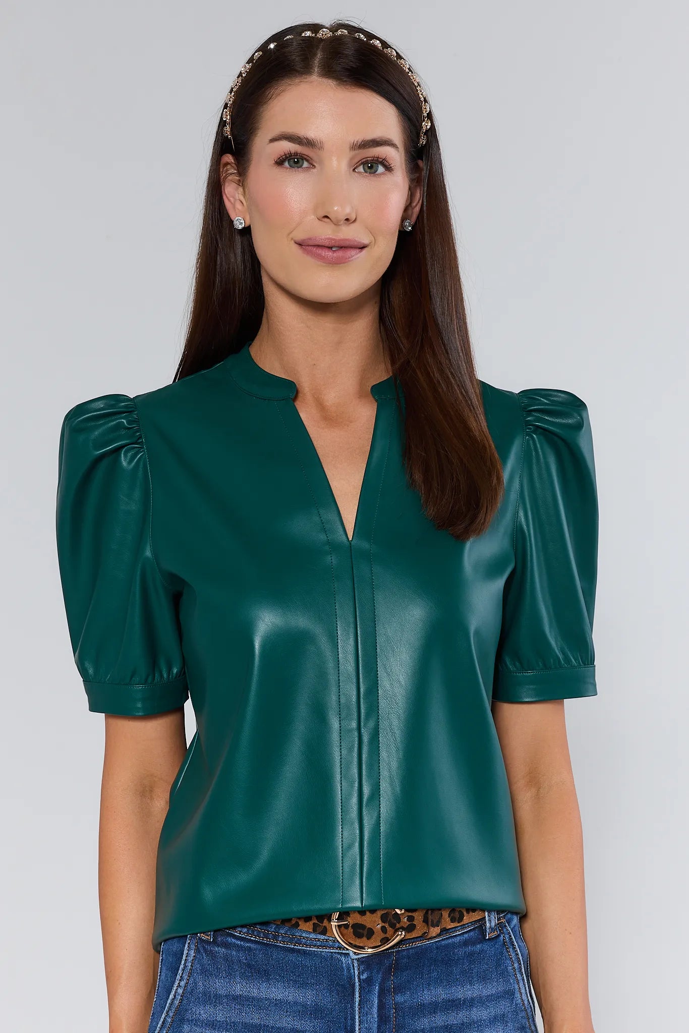 Woman wearing a green Ariana Top with puff sleeves against a plain background