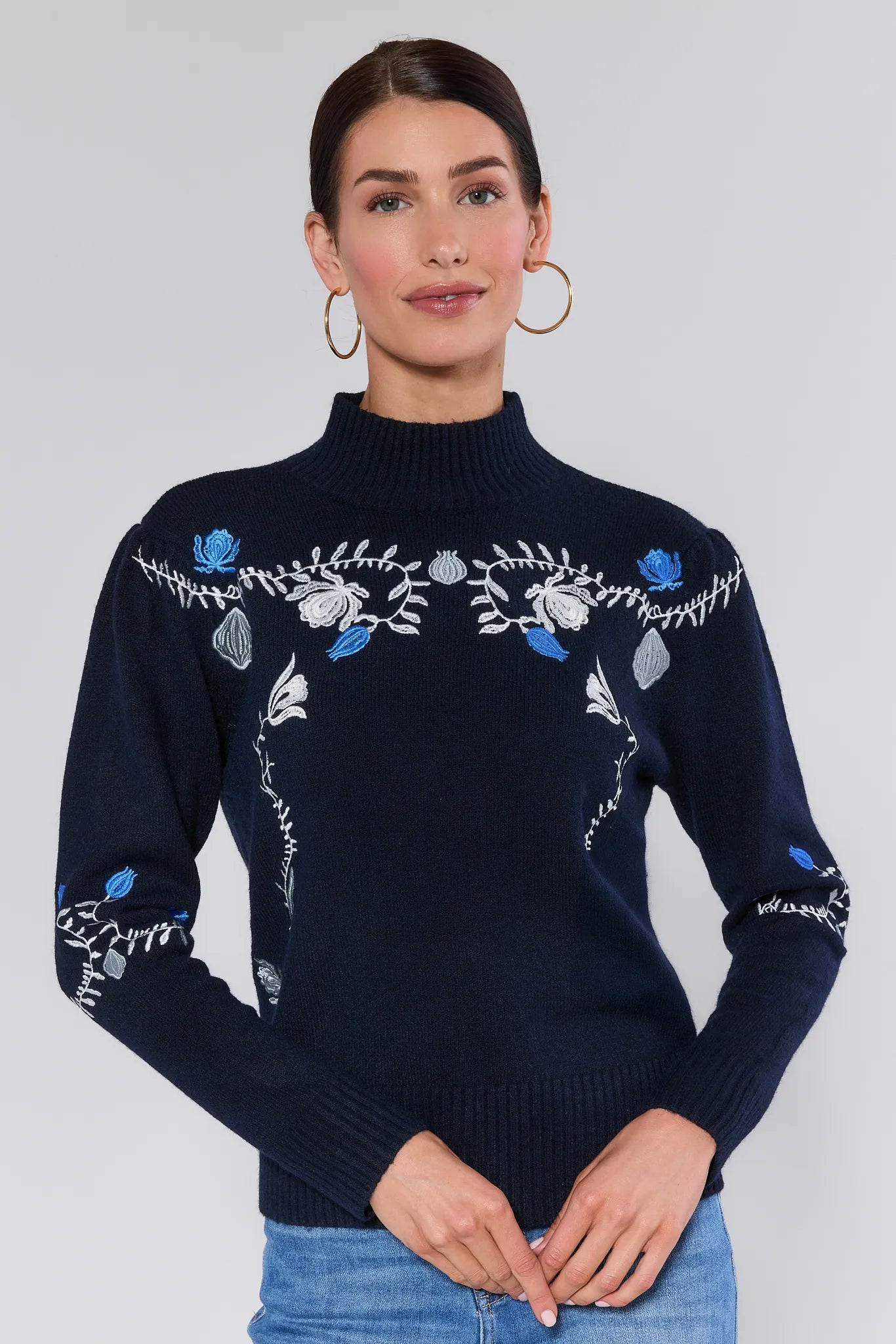 Woman wearing a Celia Blue Embroidered Knit Sweater with floral embroidery on a plain background