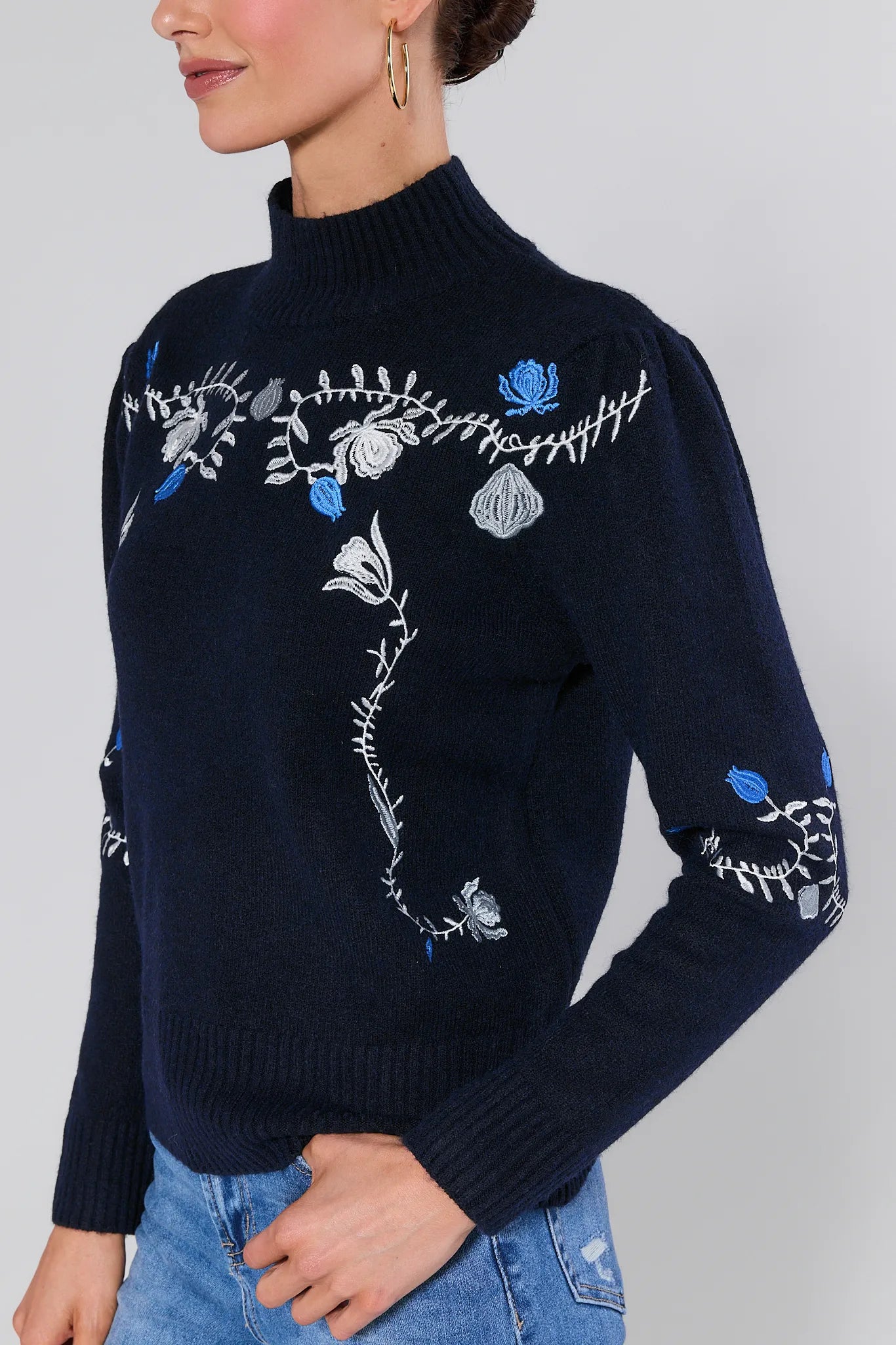 Woman wearing a Celia Blue Embroidered Knit Sweater with floral embroidery on a plain background