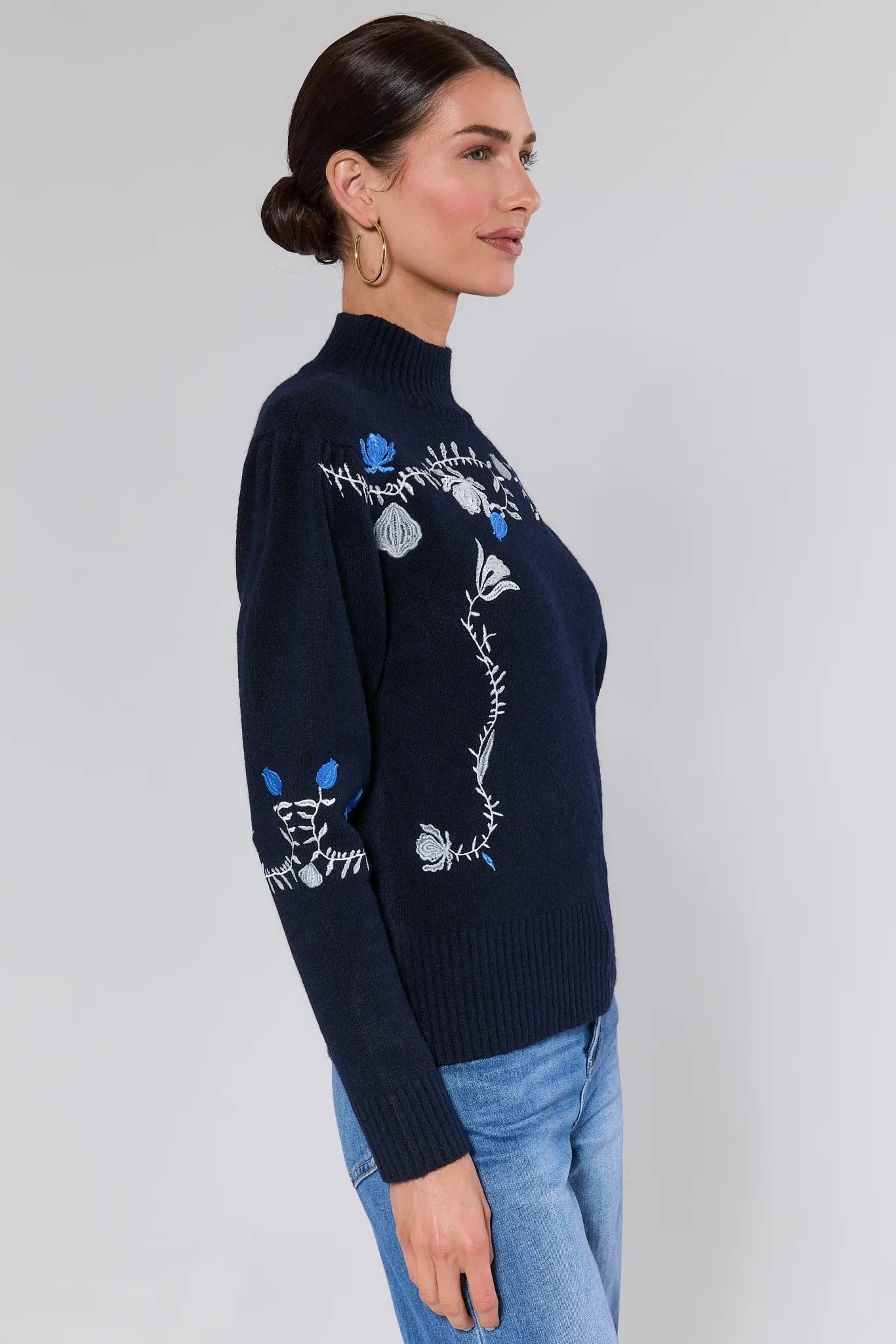 Woman wearing a Celia Blue Embroidered Knit Sweater with floral embroidery on a plain background