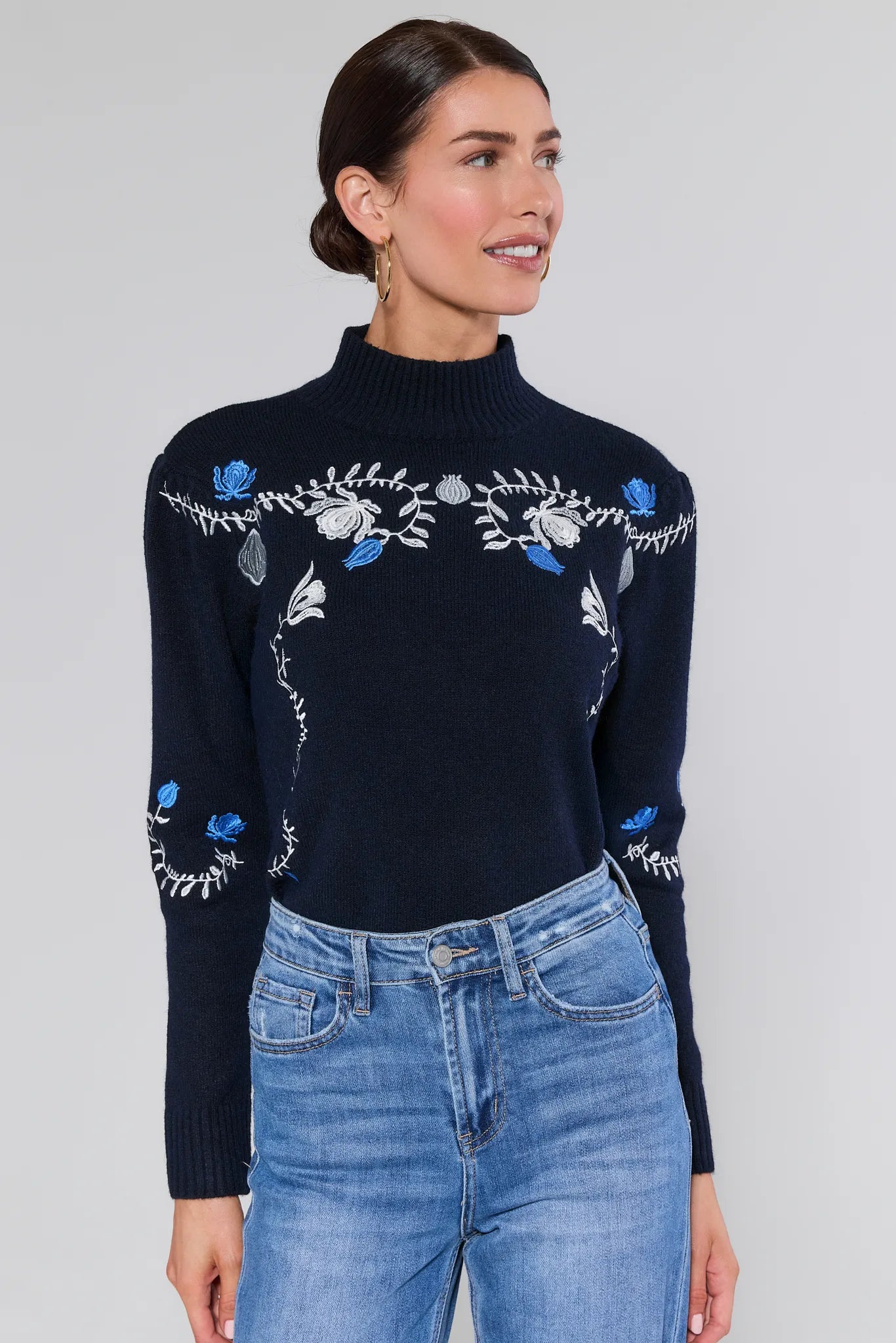 Woman wearing a Celia Blue Embroidered Knit Sweater with floral embroidery on a plain background