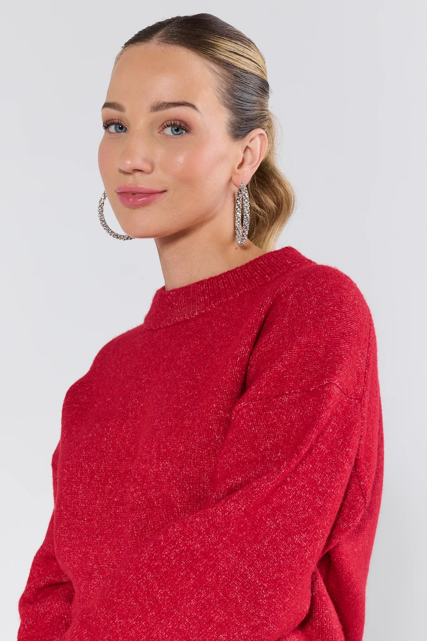 Woman wearing a red sweater with a plain background