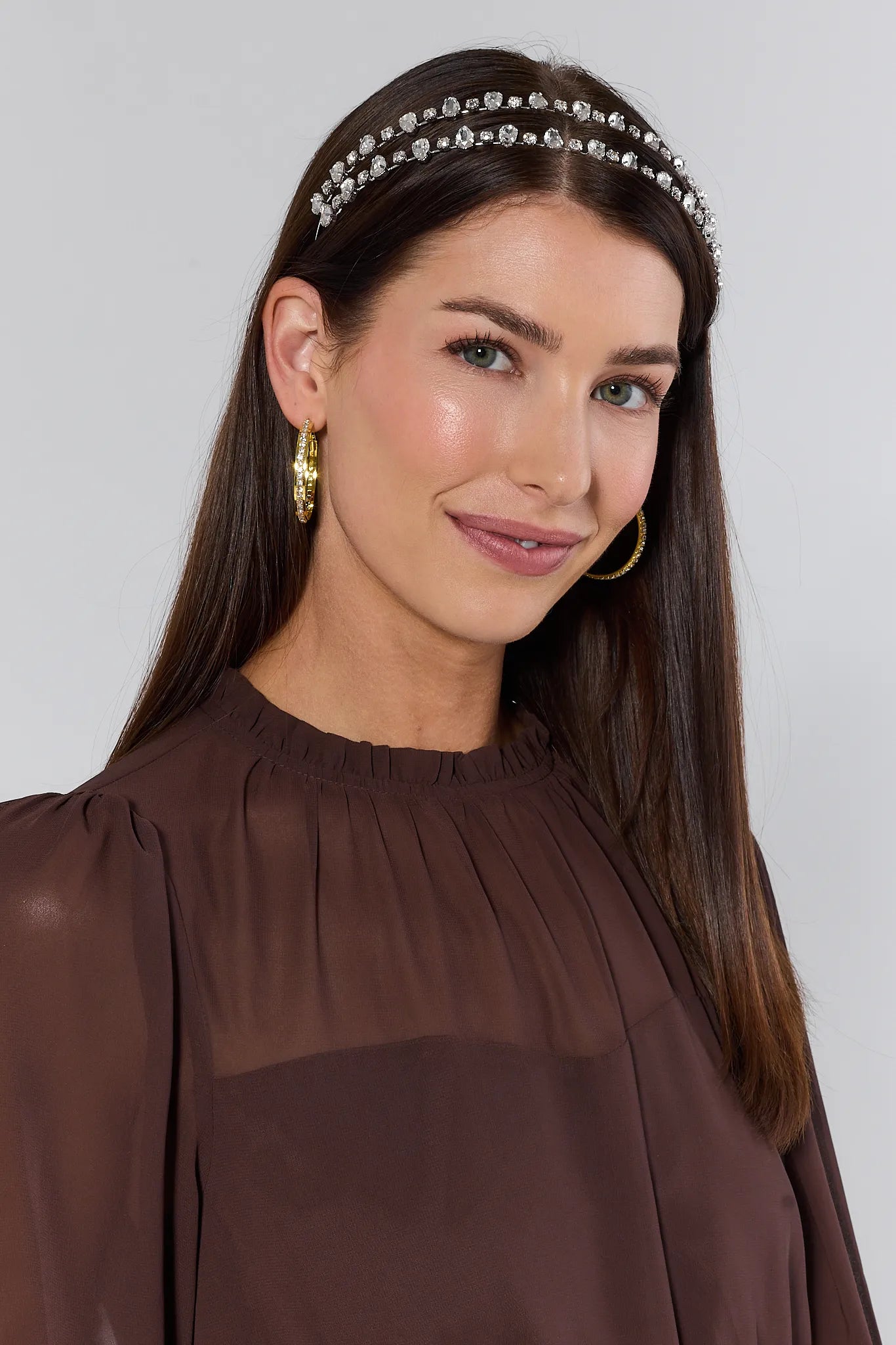 Woman wearing a brown top and Anne Rhinestone Headband with a plain background