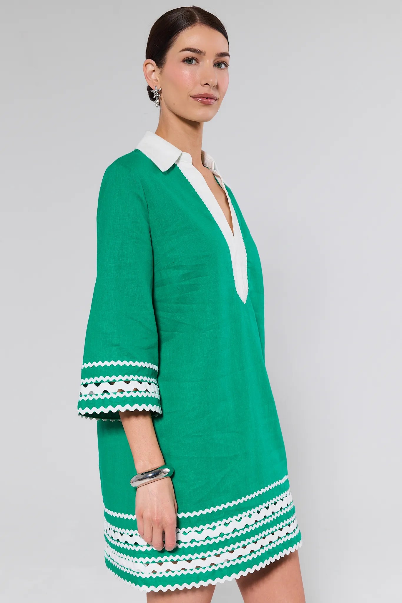 Woman wearing a green dress with white trim on a gray background