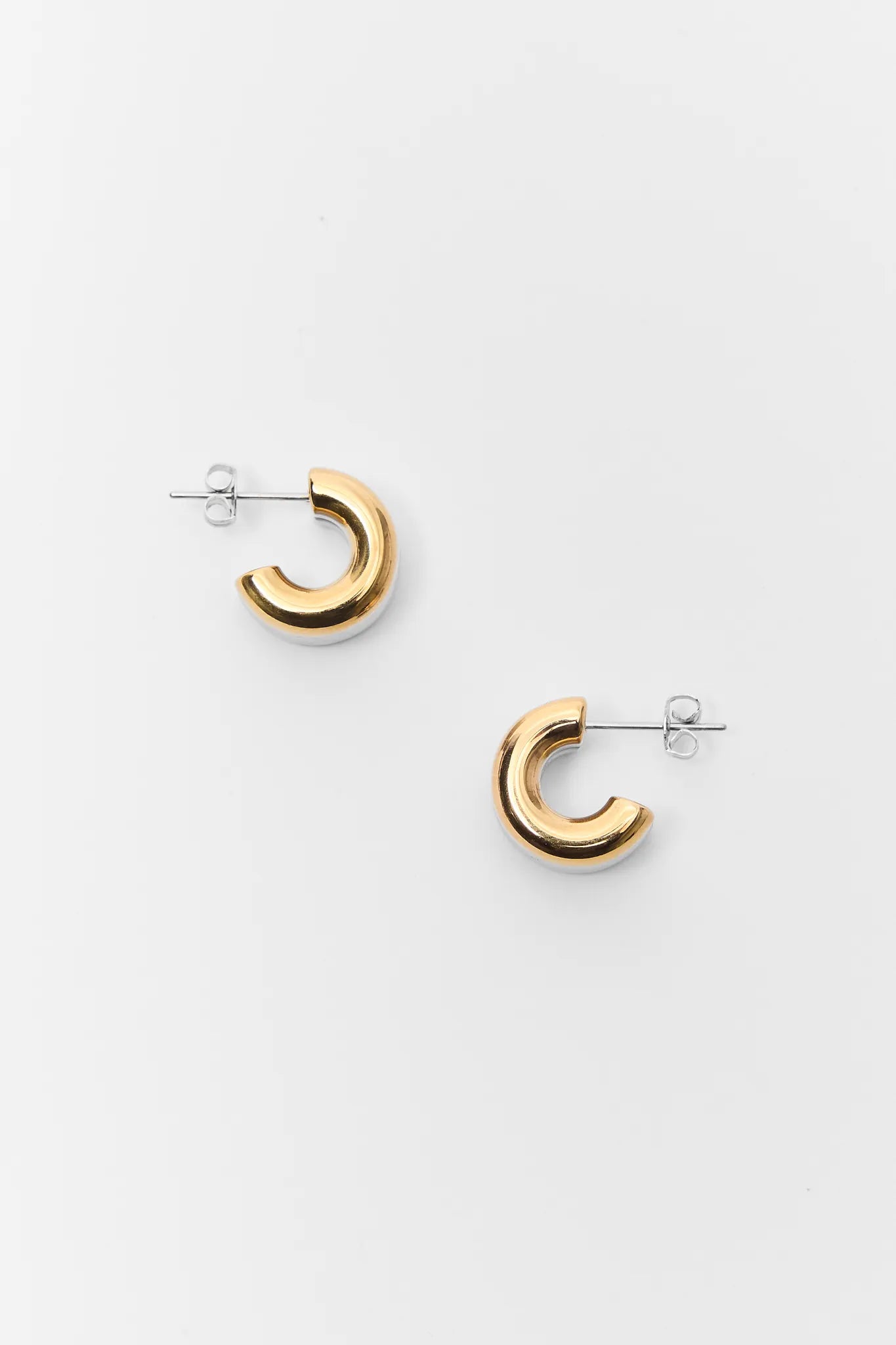 Gold hoop earrings on a white background Emma Two Toned Huggie Earrings