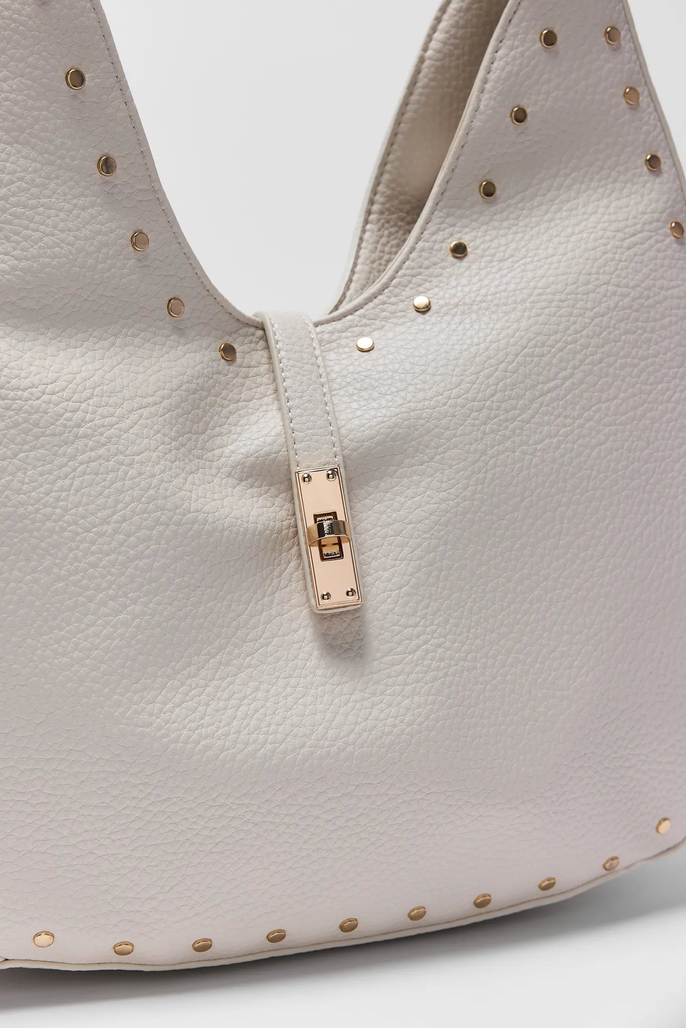 Close-up of a Olivia Cream Slouchy Shoulder Bag with gold studs on a white background