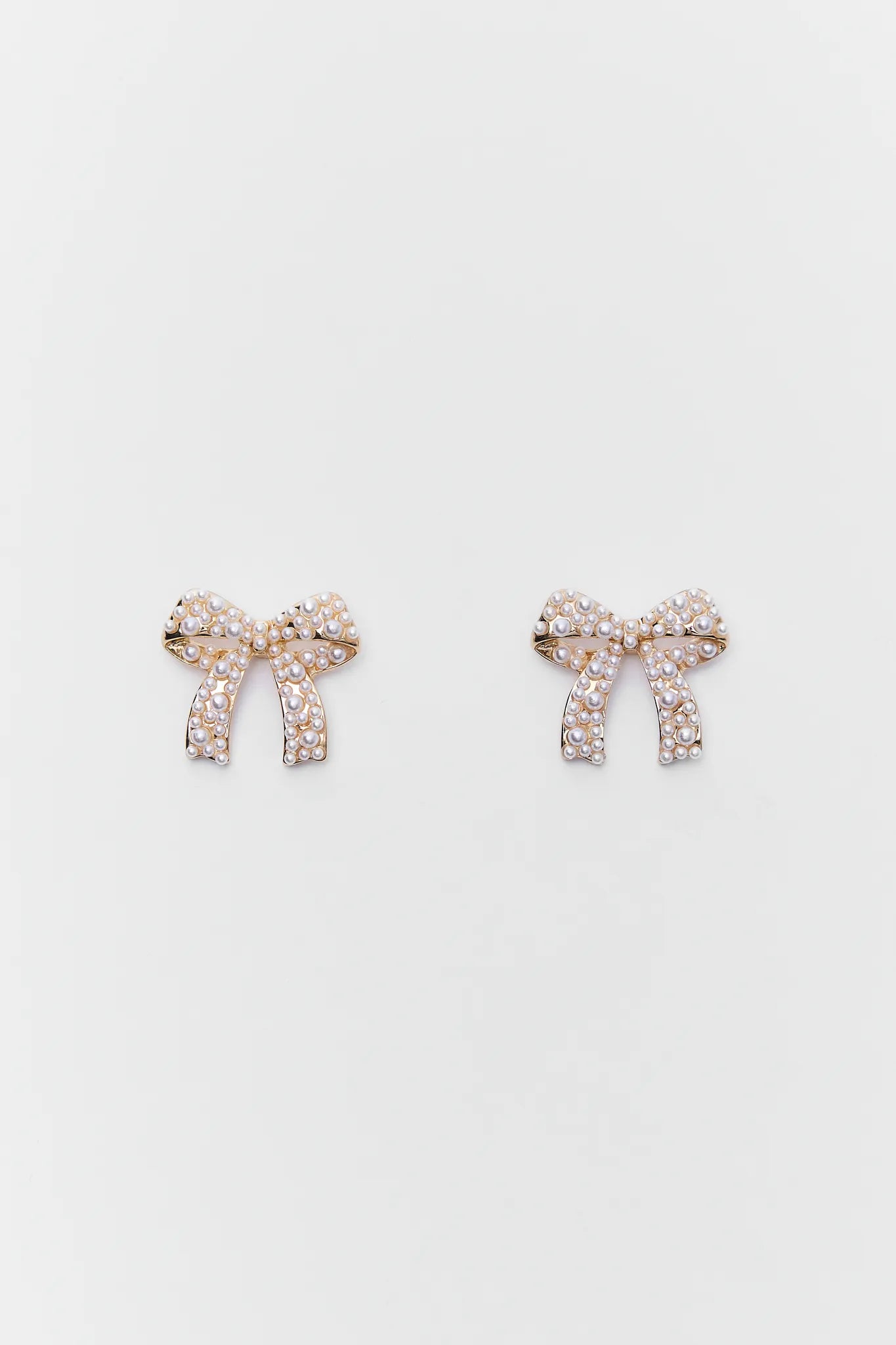 Paige Gold Bow Earrings with rhinestones on a light gray background