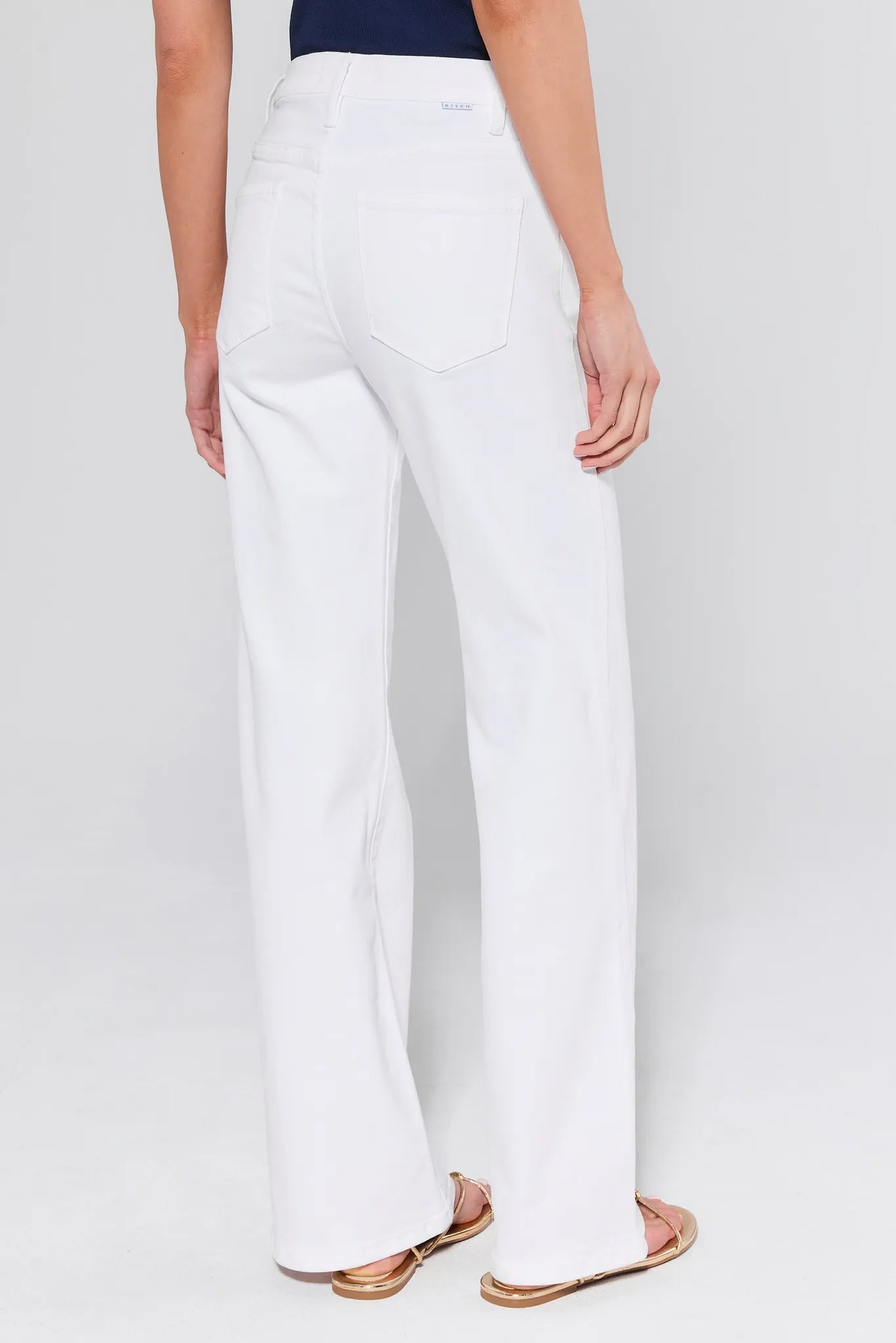 Person wearing white pants on a plain background