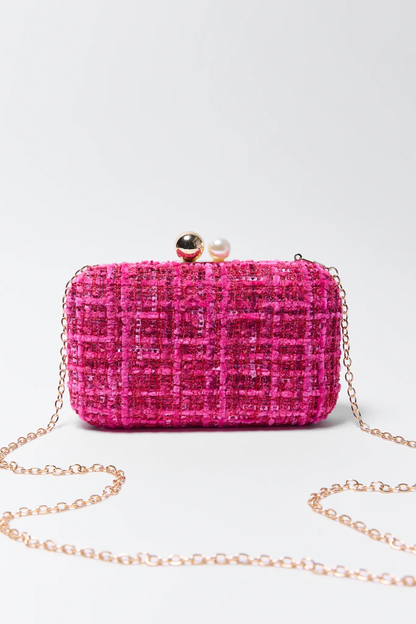Pink tweed Mabel clutch bag with a chain strap on a light gray background
