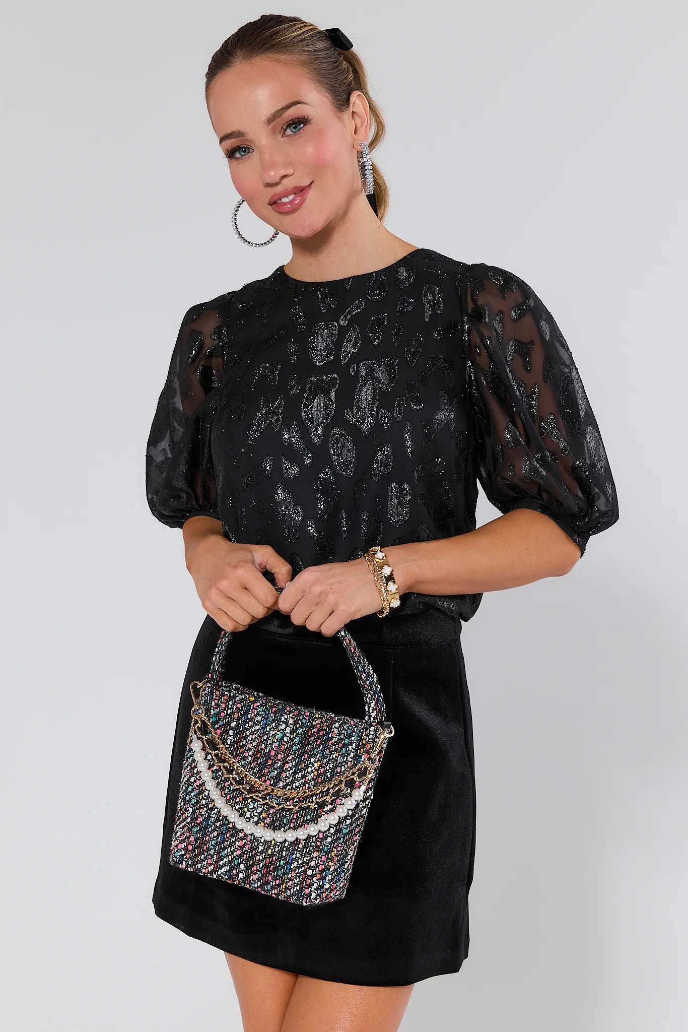 Woman holding a patterned chloe handbag wearing a black dress against a white background