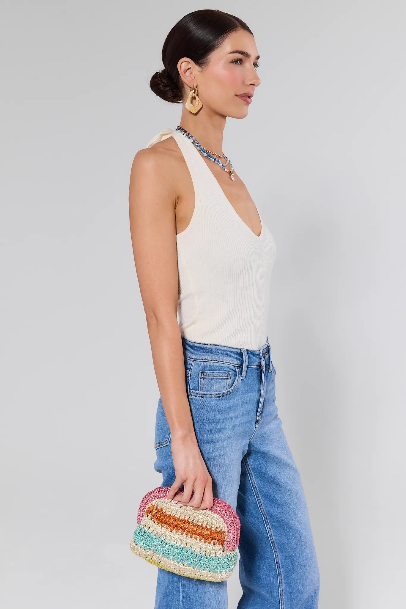 Woman holding a colorful clutch against a plain background