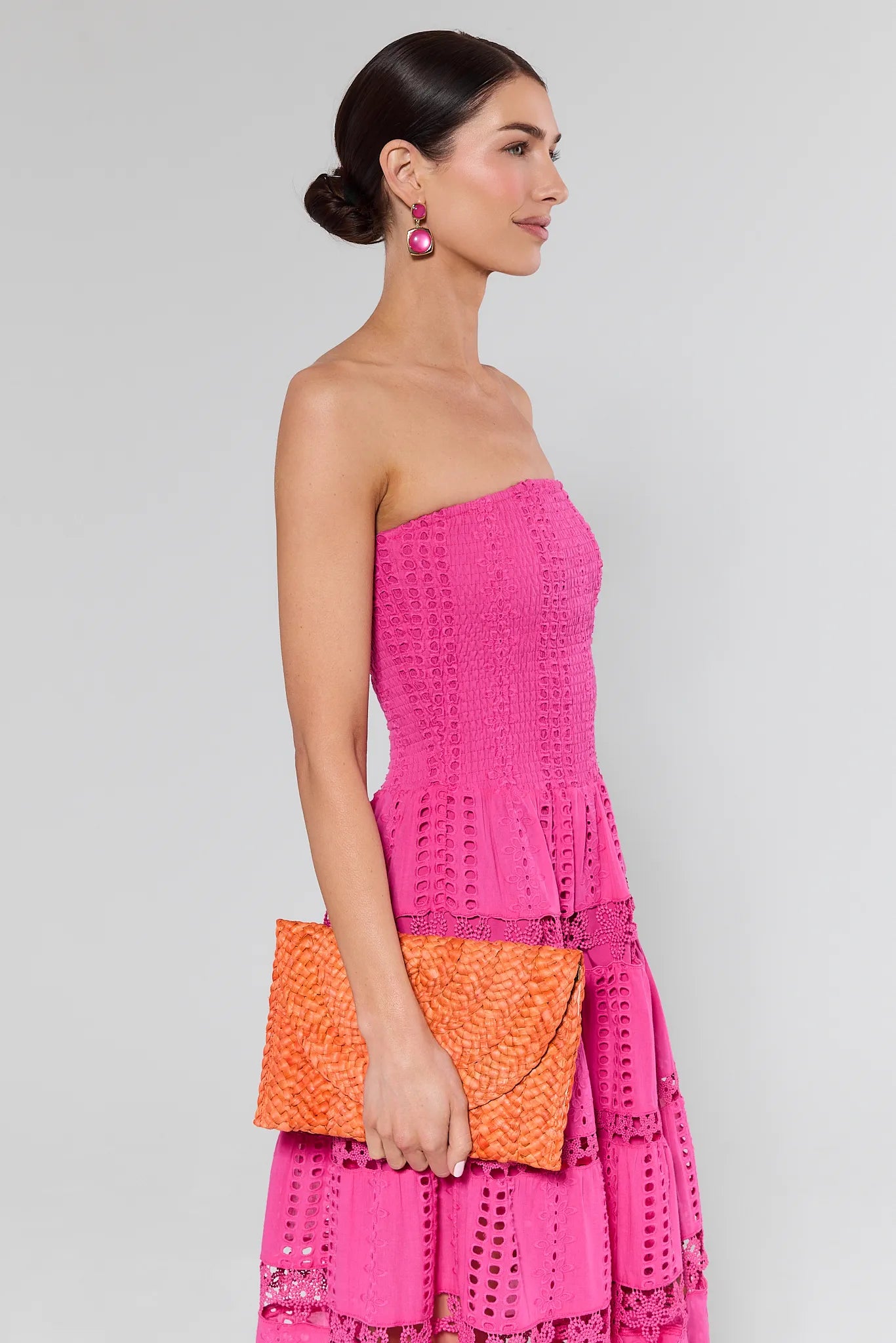 woman in pink dress holding orange woven clutch