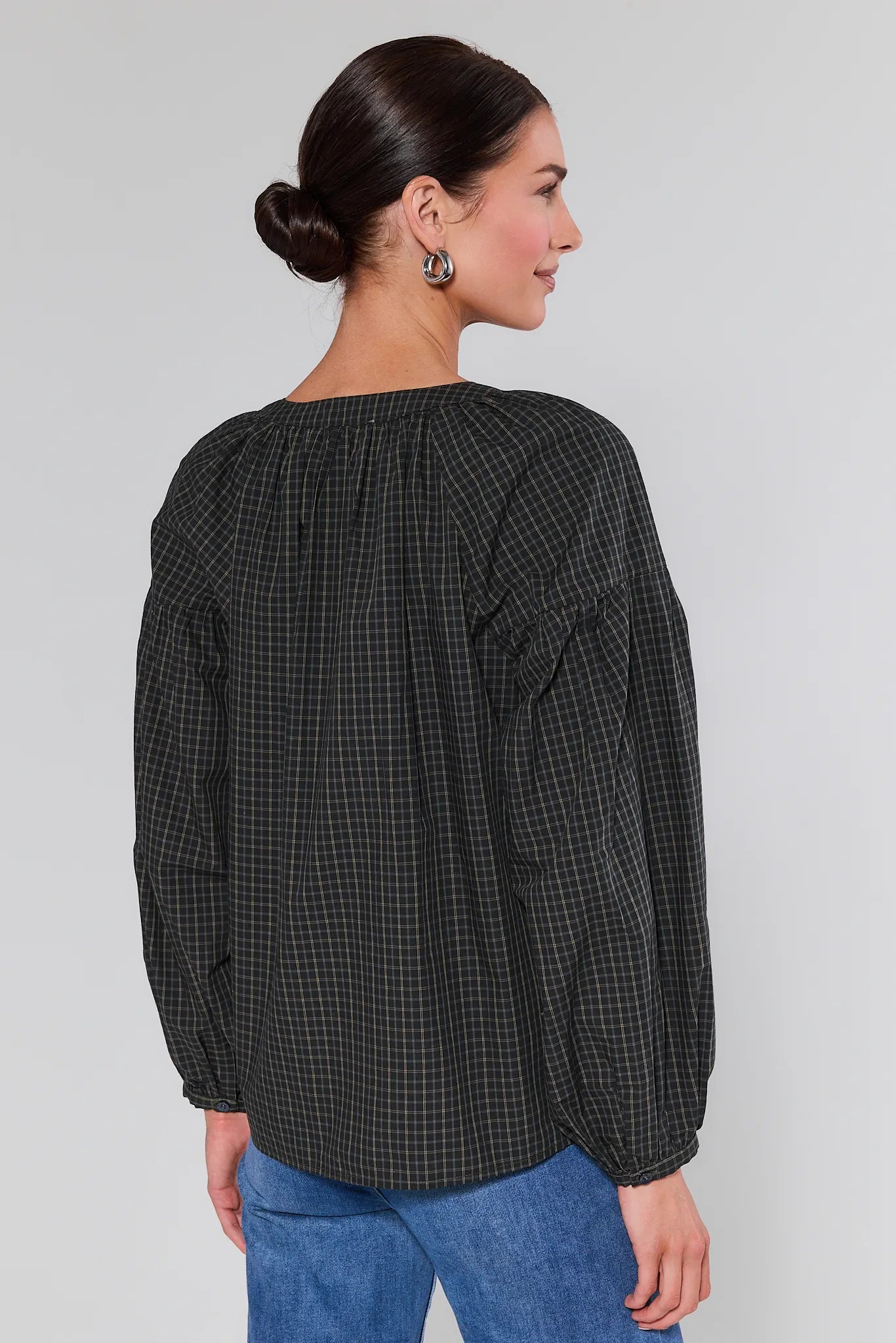 Woman wearing a Sammy Plaid Button Up Top and blue jeans against a plain background