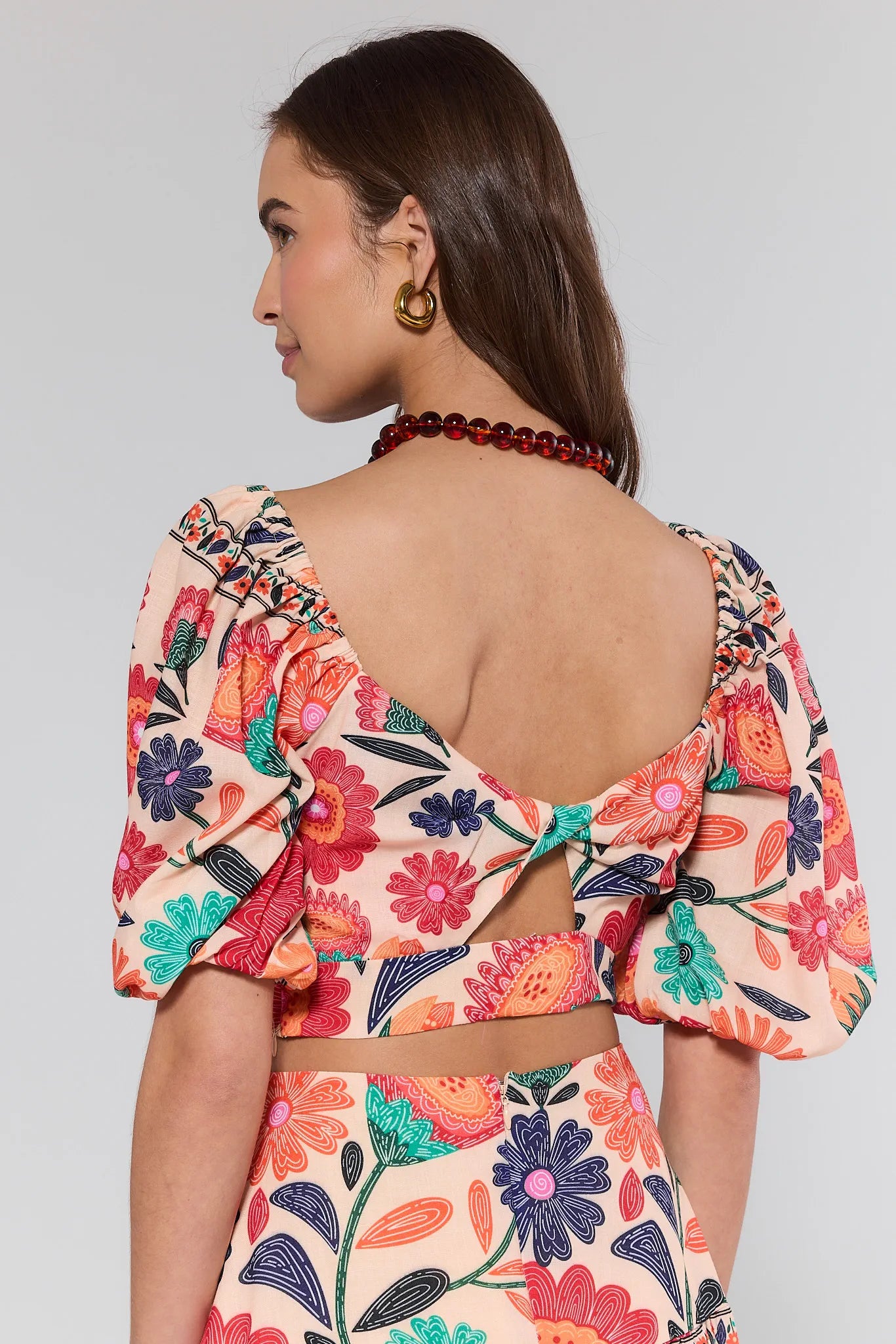 Woman wearing a colorful floral dress with a plain background