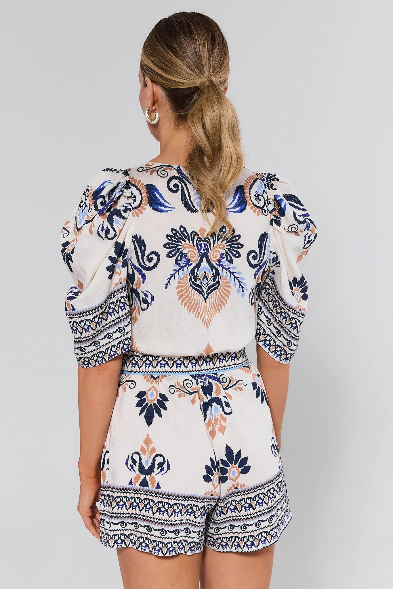 Woman wearing a romper on a plain background