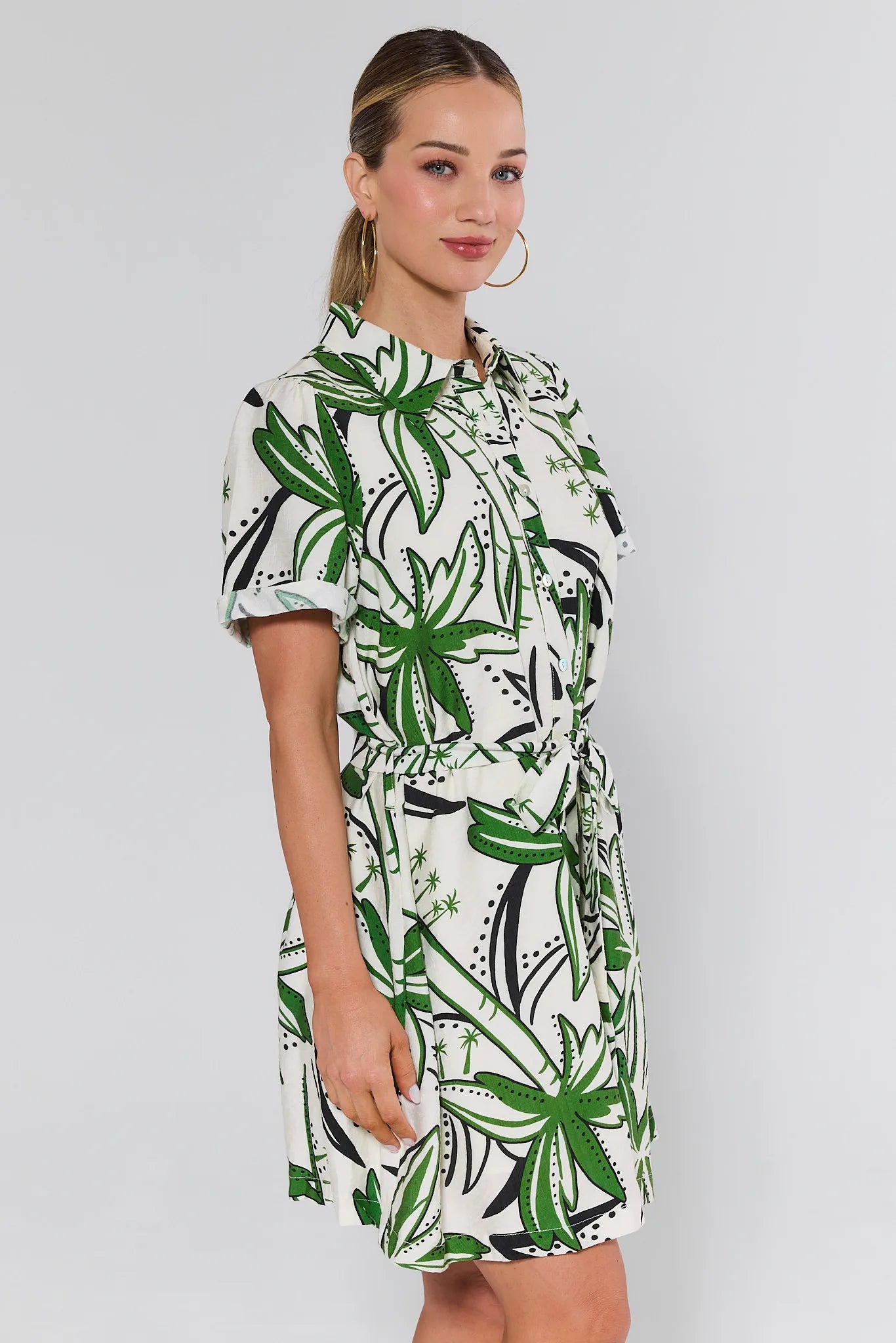 Woman wearing a green and white patterned dress on a plain background