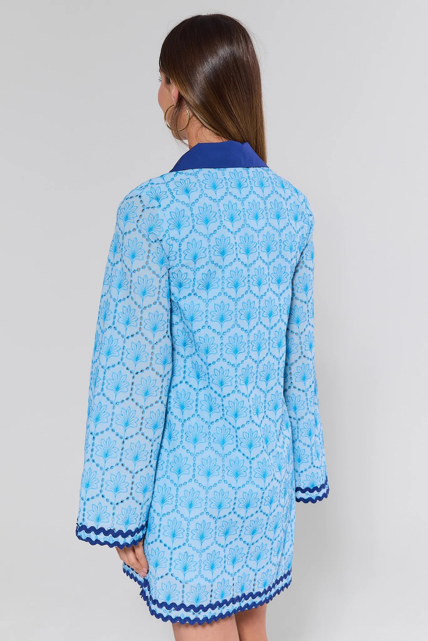 Woman wearing a blue patterned dress with a white background