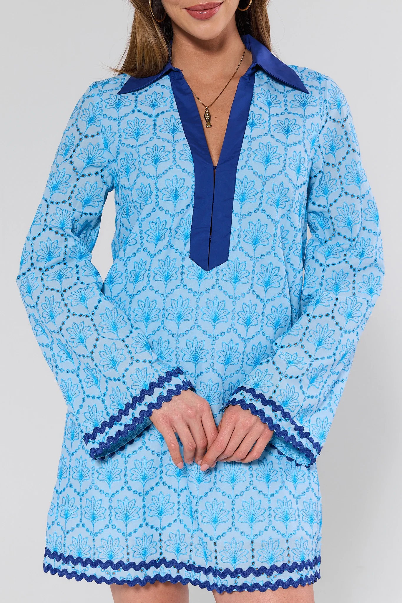 Woman wearing a blue patterned dress with a white background
