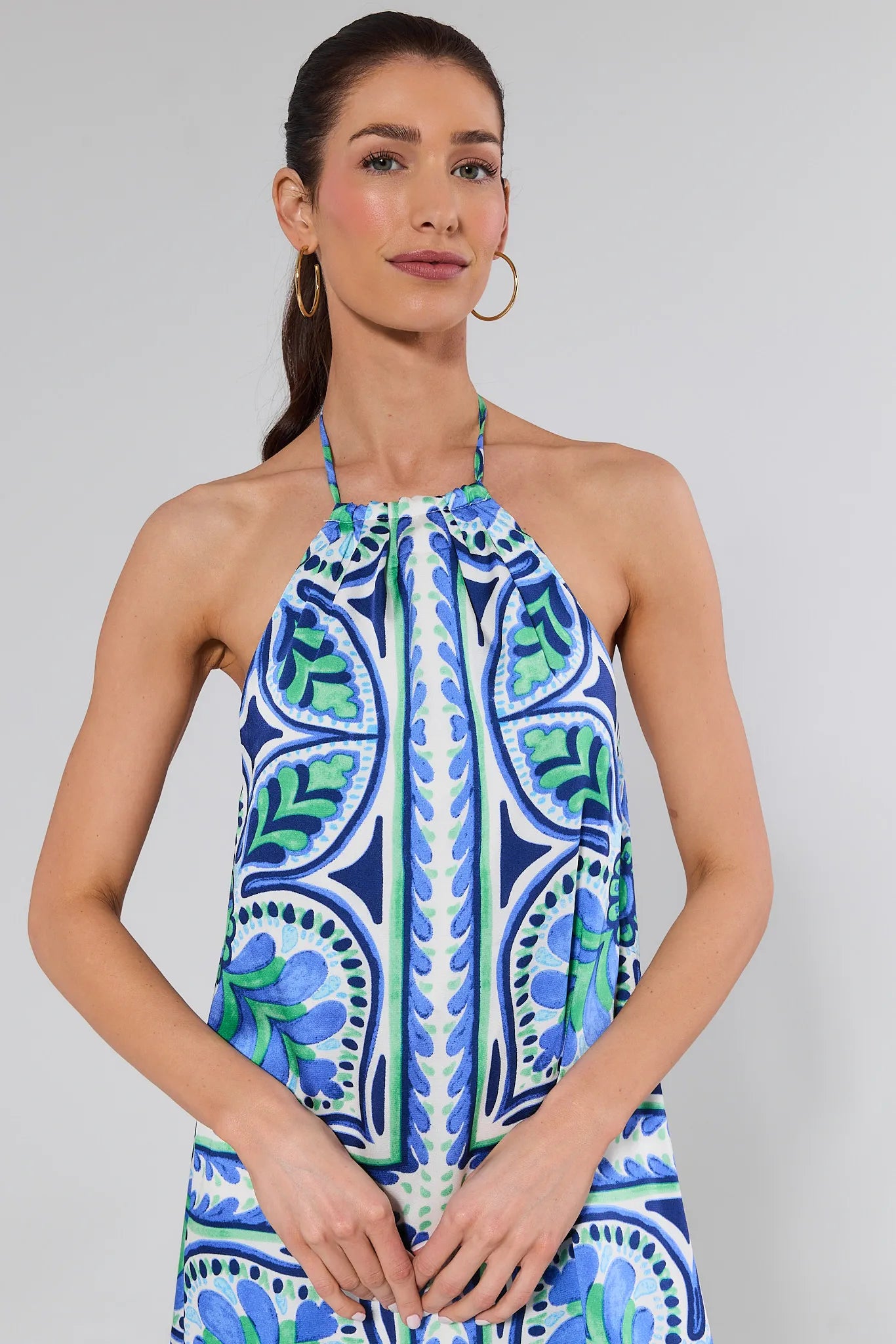 Woman wearing a blue and green patterned dress against a gray background