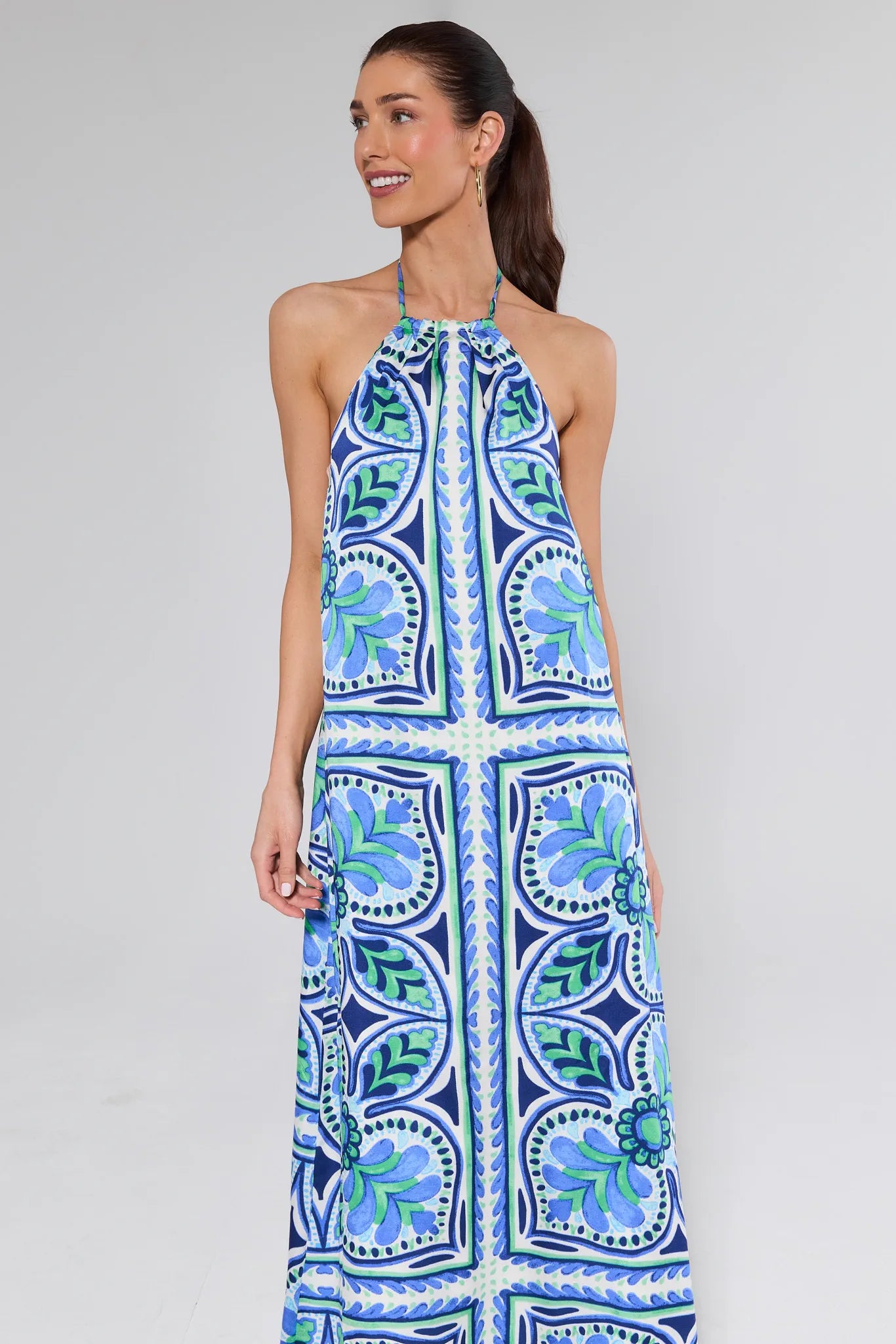 Woman wearing a blue and green patterned dress on a gray background