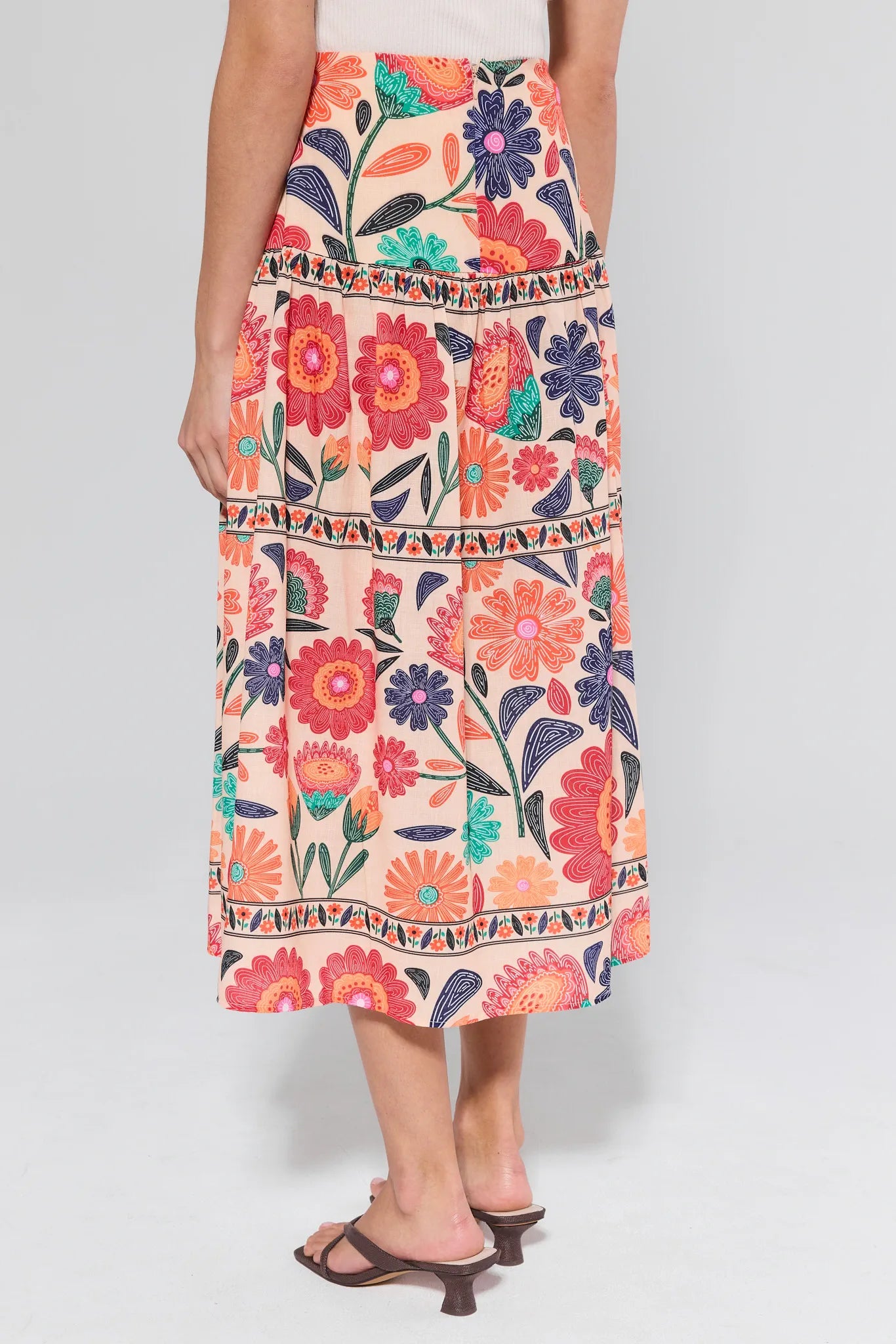 Colorful floral skirt worn by a person on a plain background