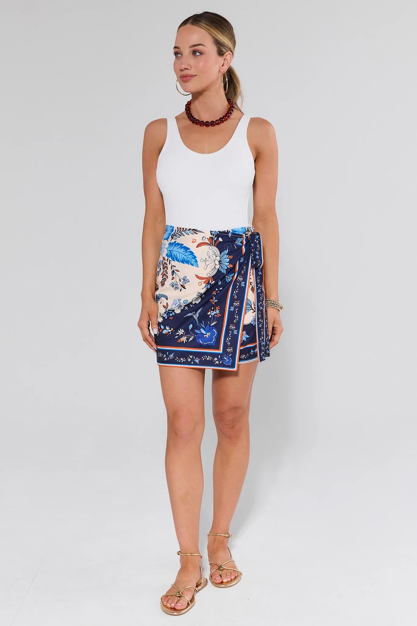 Woman wearing a white top and a colorful patterned skirt on a white background