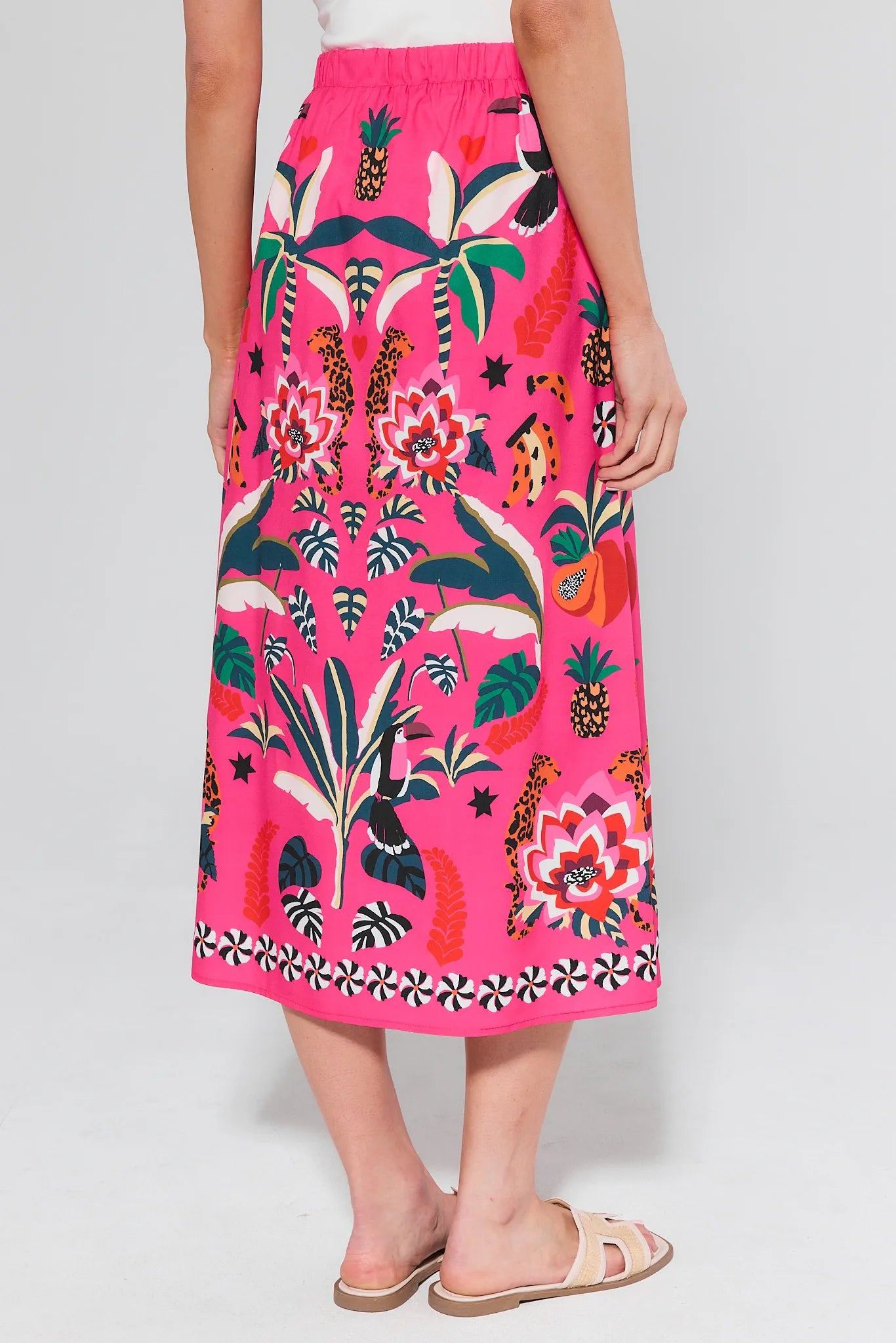 Person wearing a bright pink skirt with colorful floral and animal pattern on a white background