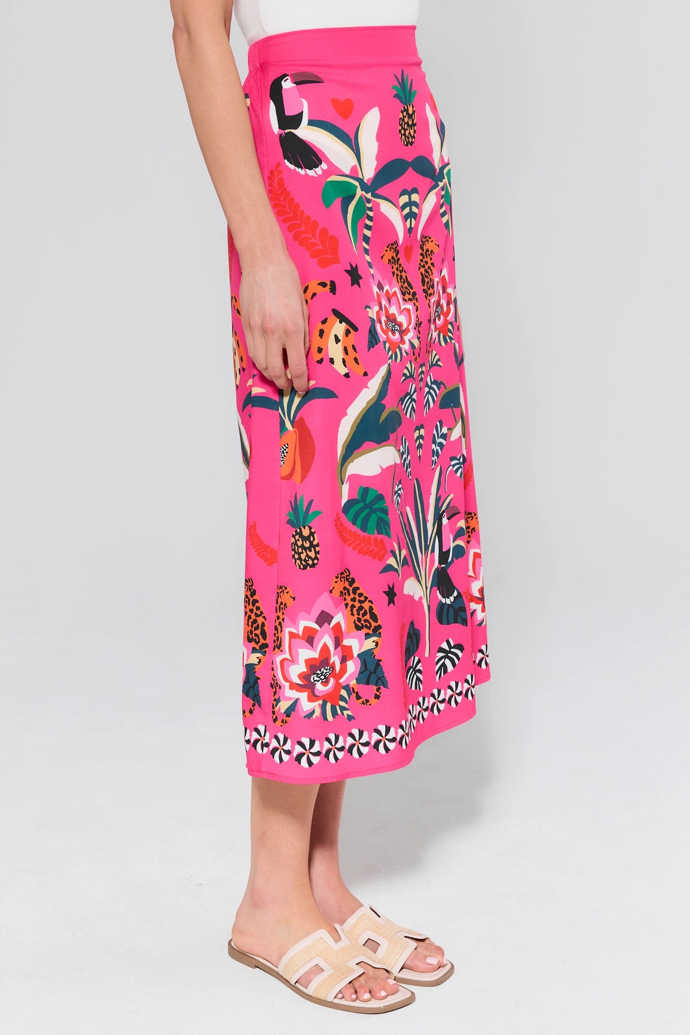 Person wearing a bright pink skirt with colorful floral and animal pattern on a white background