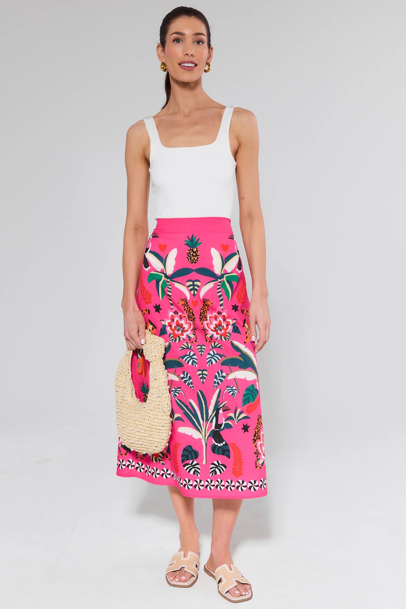 Woman wearing a white tank top and pink floral skirt on a gray background