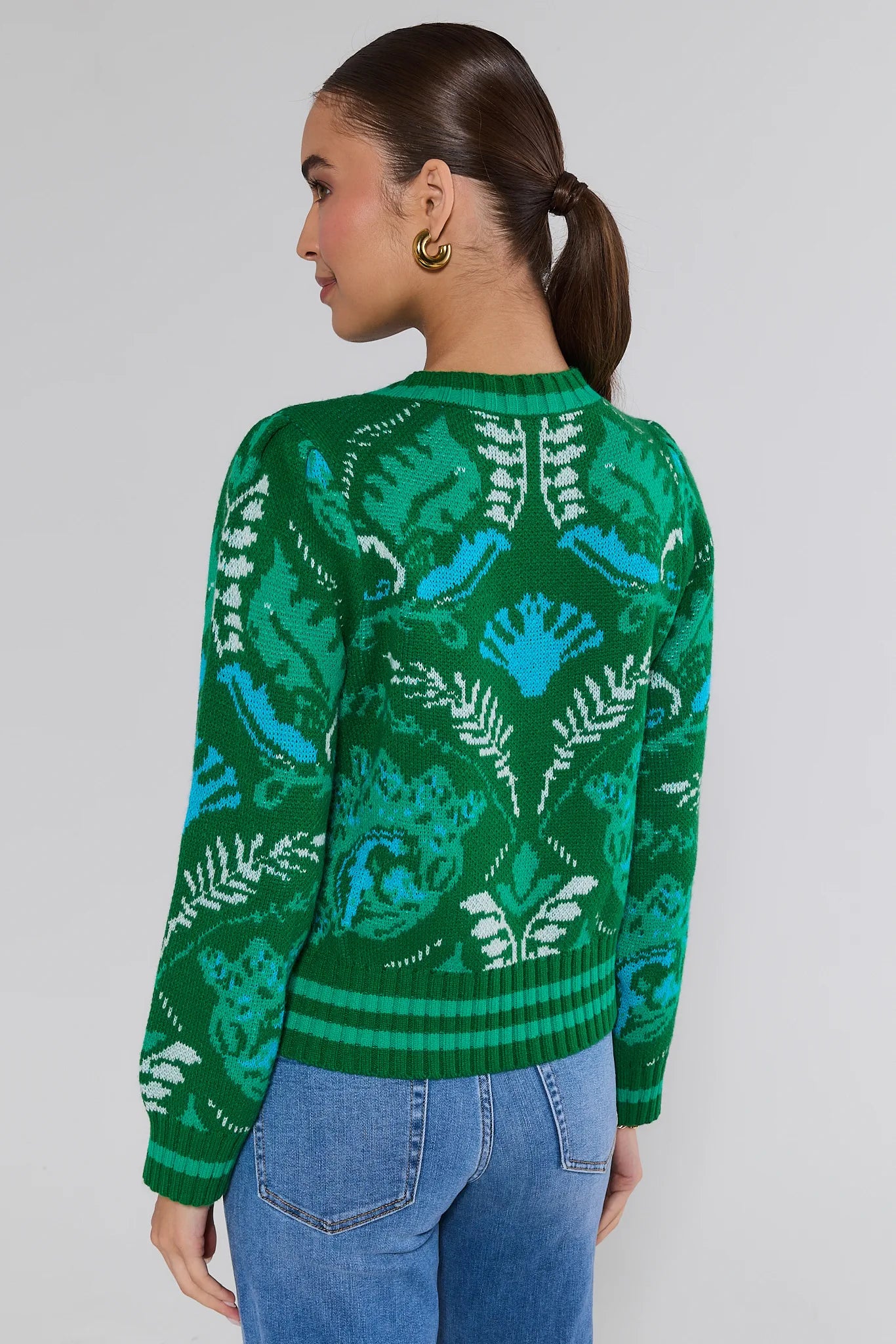 Person wearing a green patterned sweater against a plain background