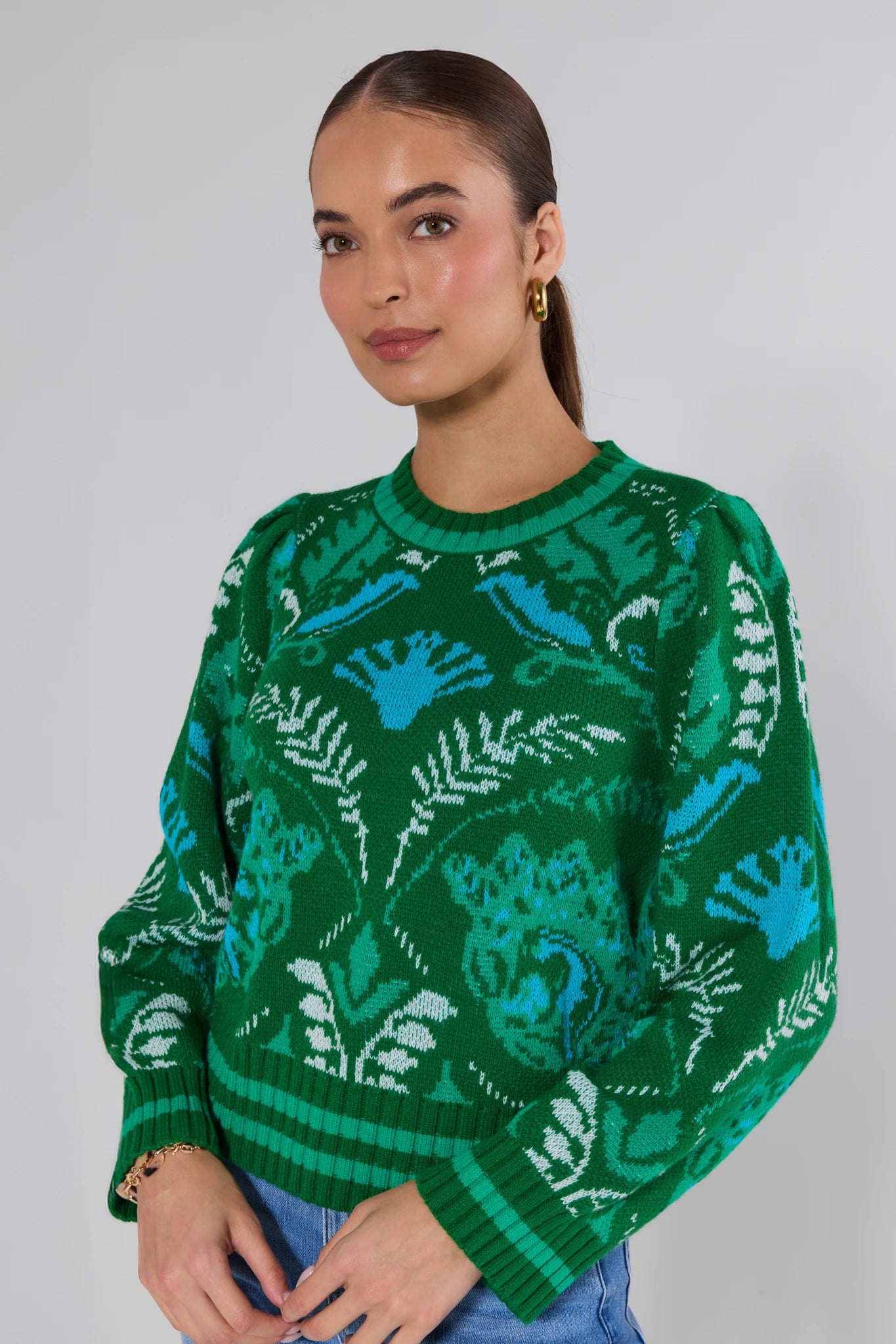 Woman wearing a green patterned sweater against a plain background