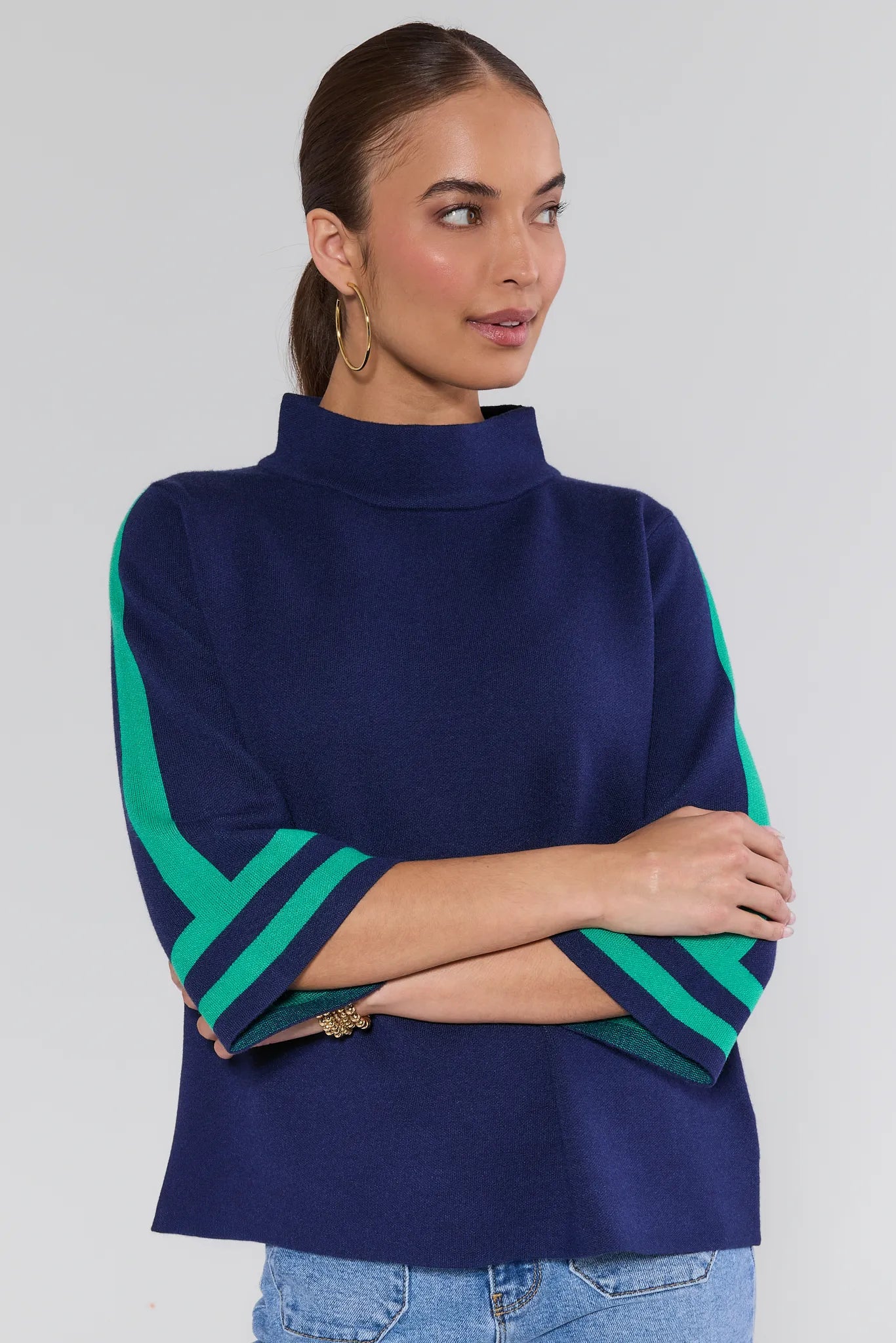 Woman wearing a navy sweater with green sleeves against a white background
