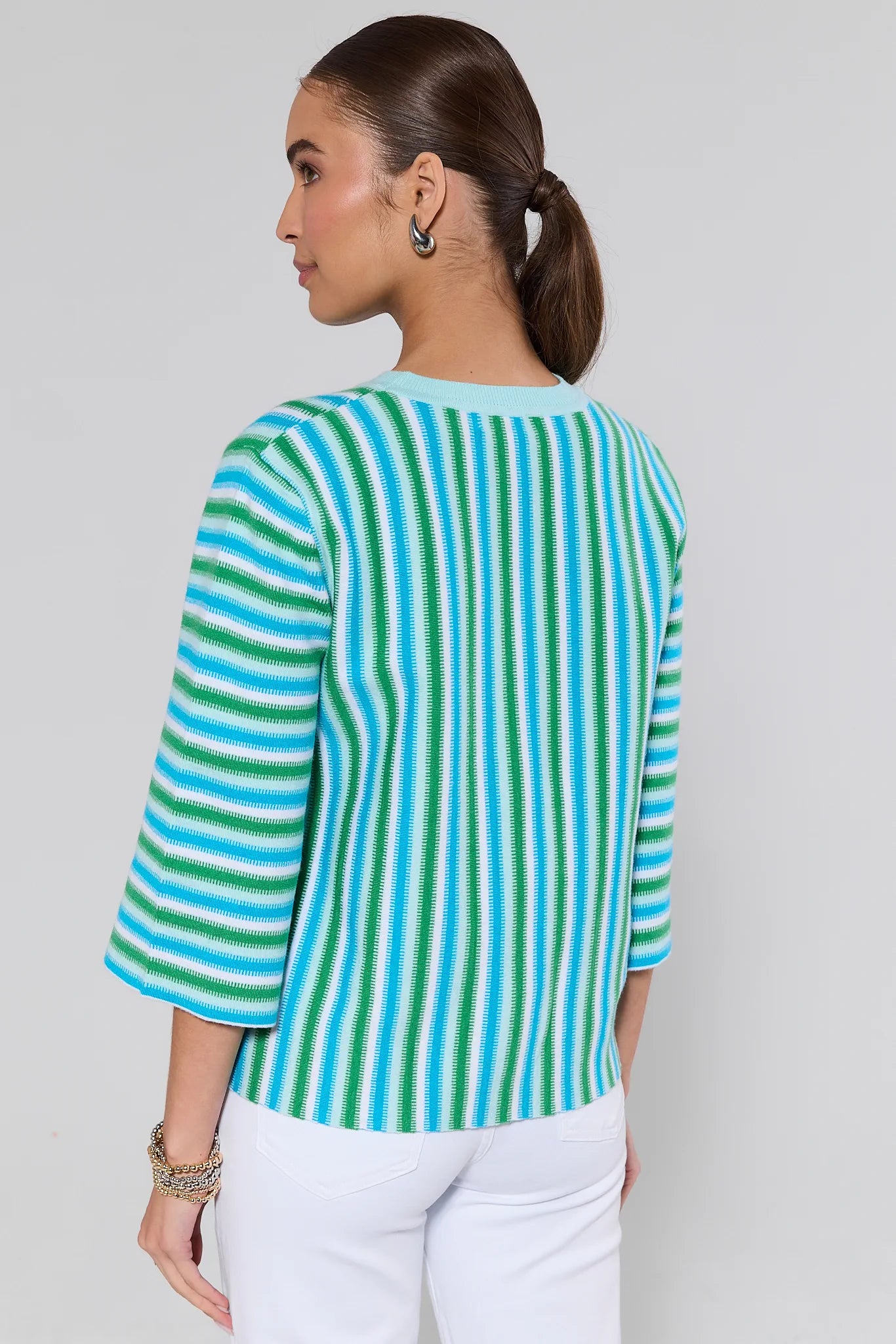 Woman wearing a blue and green striped shirt against a plain background