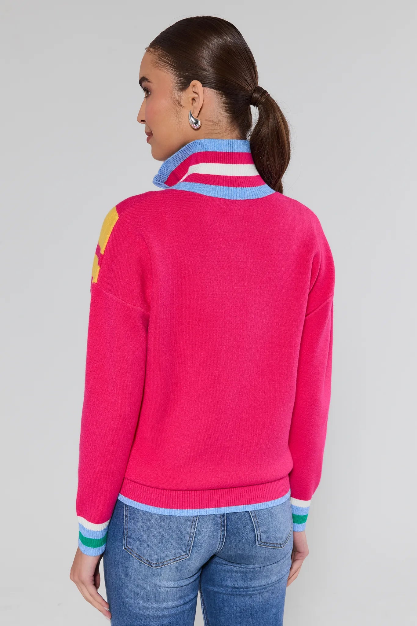Person wearing a bright pink sweater with colorful accents on a plain background