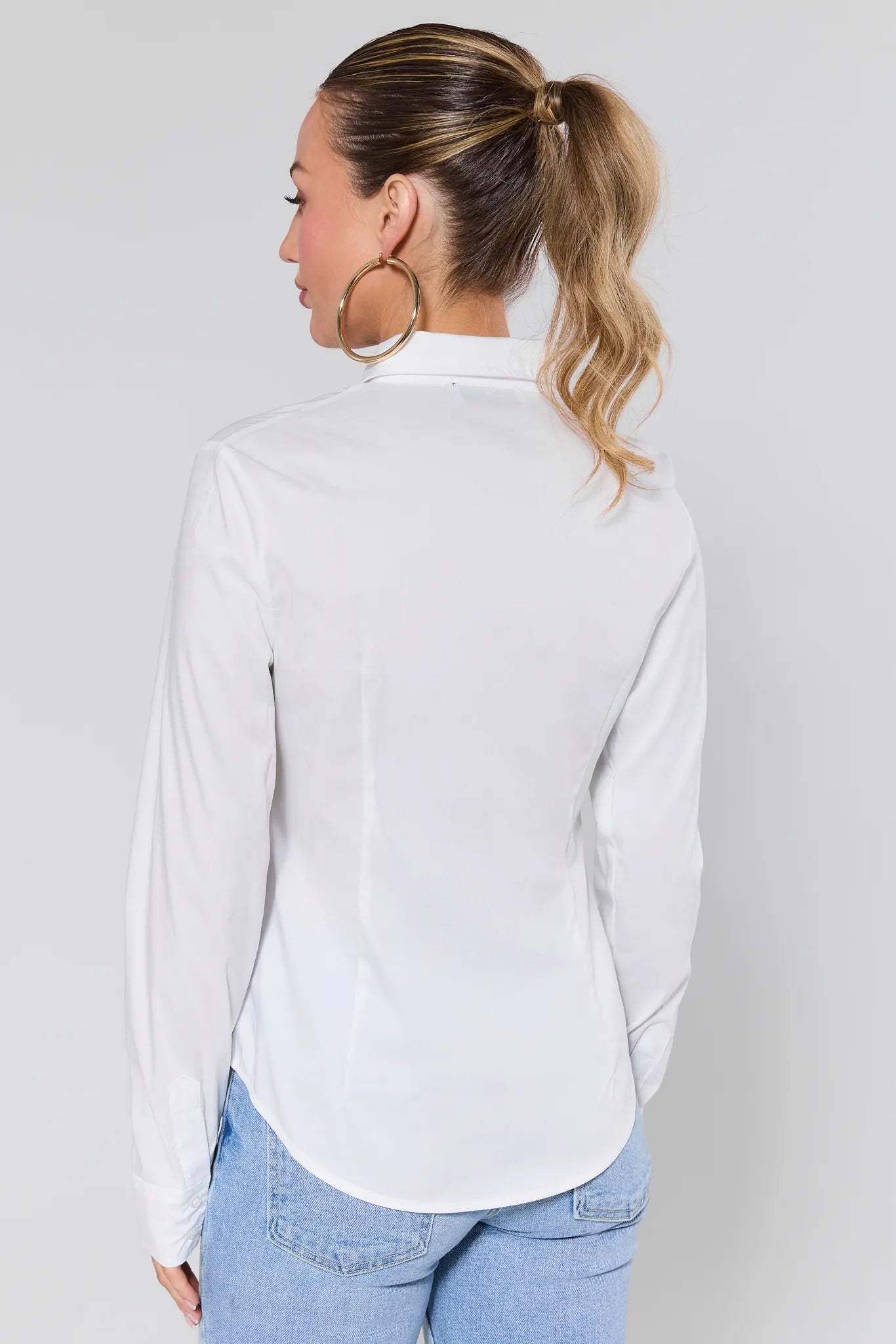Woman wearing a Pacey White Button Up Top and light blue jeans against a plain background