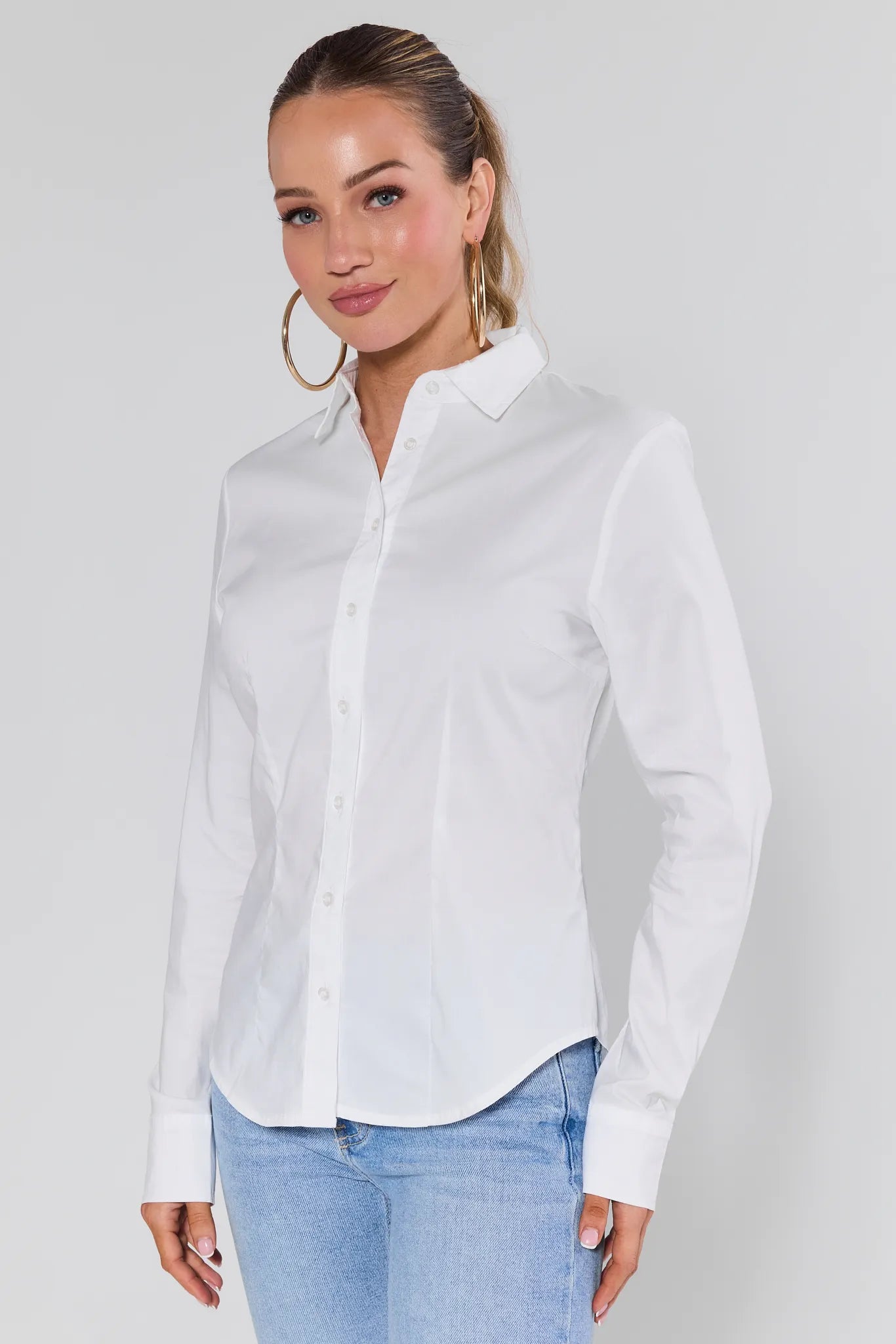 Woman wearing a Pacey White Button Up Top and light blue jeans against a plain background