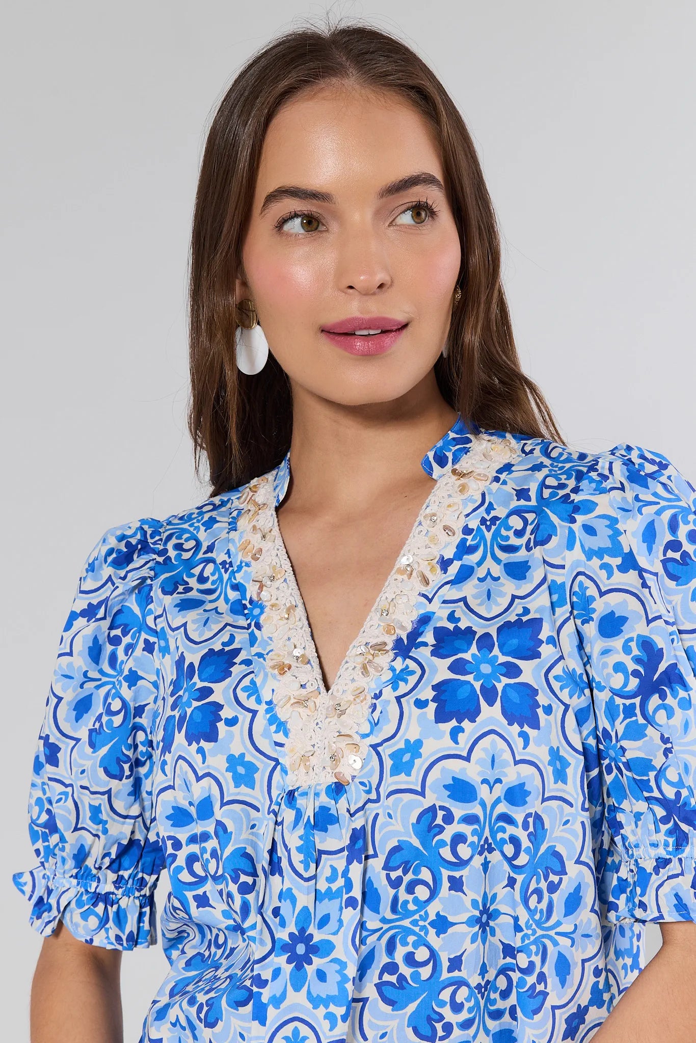 Woman wearing a blue floral dress against a plain background