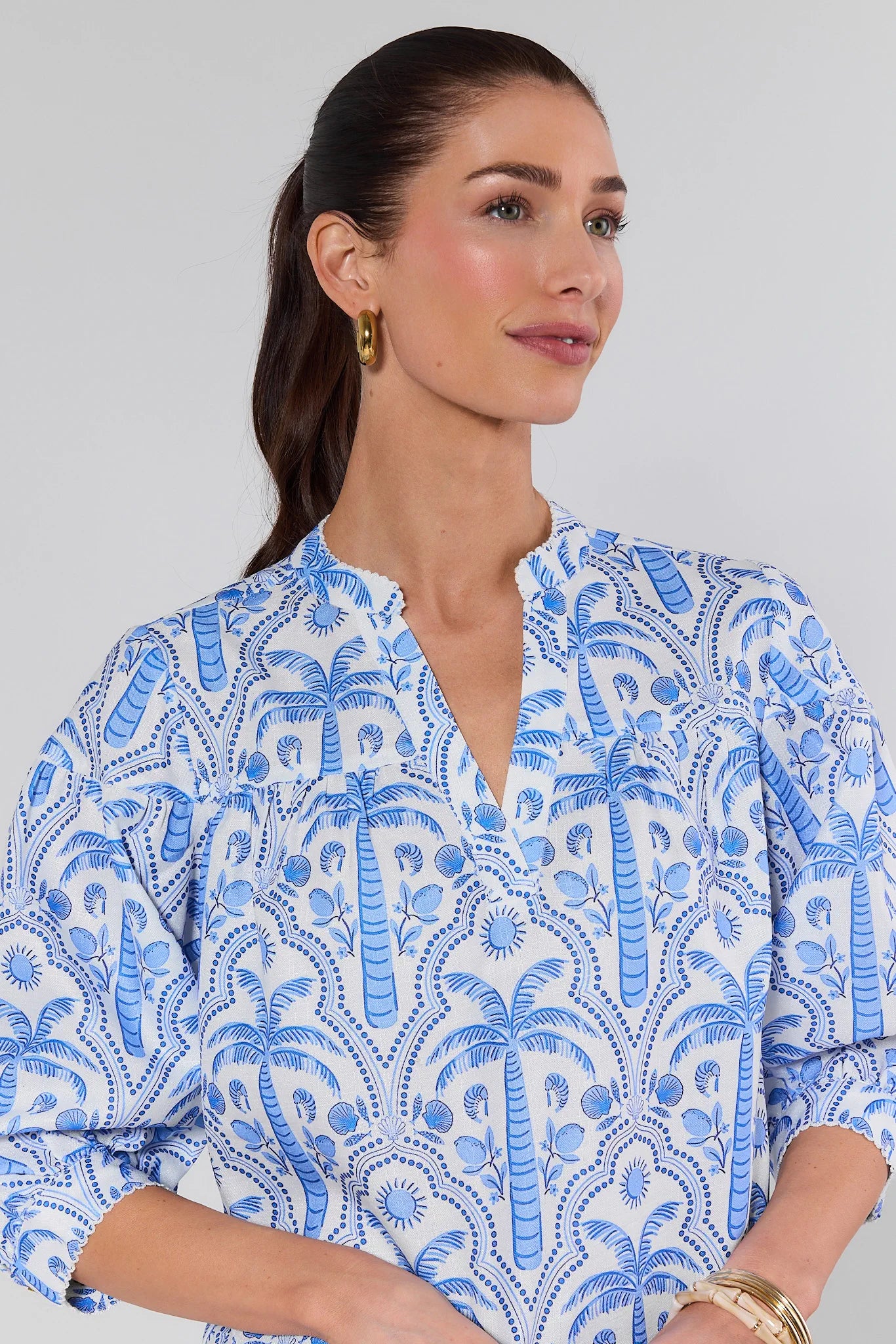 Woman wearing a blue and white patterned shirt against a plain background