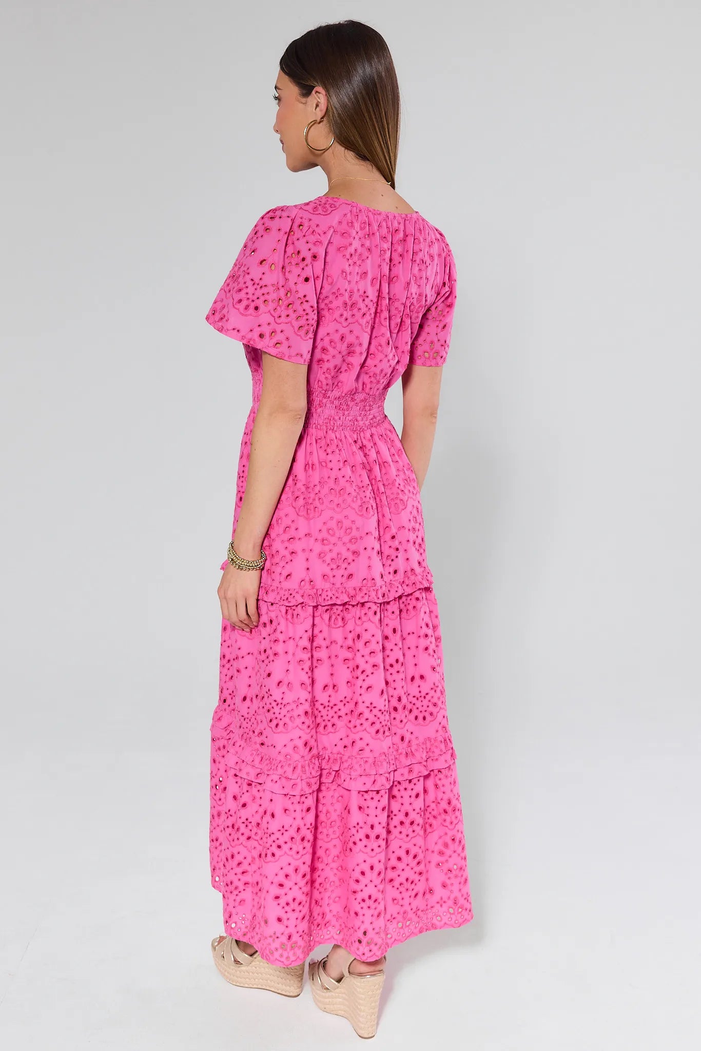 Woman wearing a pink dress with a floral pattern on a white background