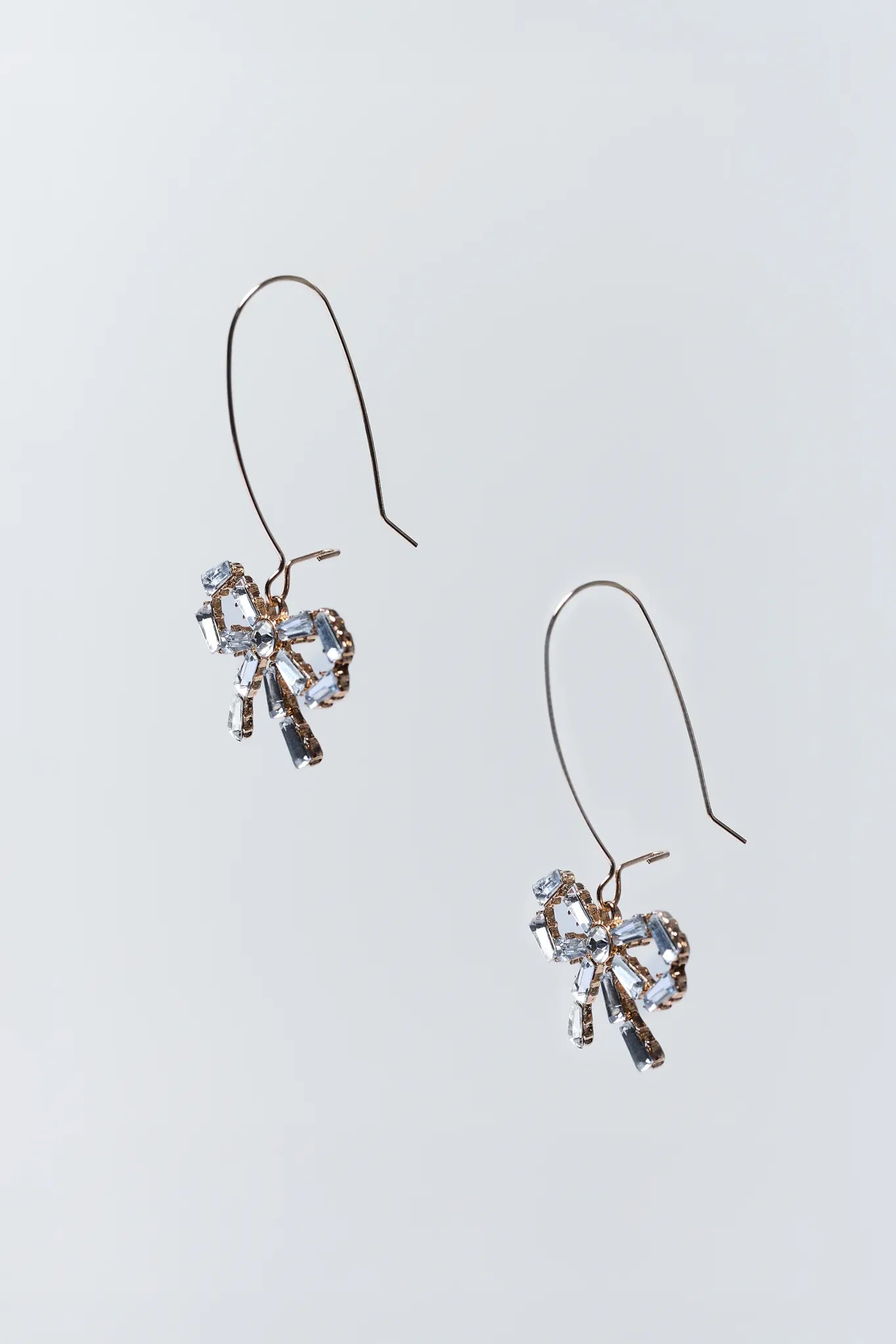 Heart-shaped earrings with clear stones on a light gray background