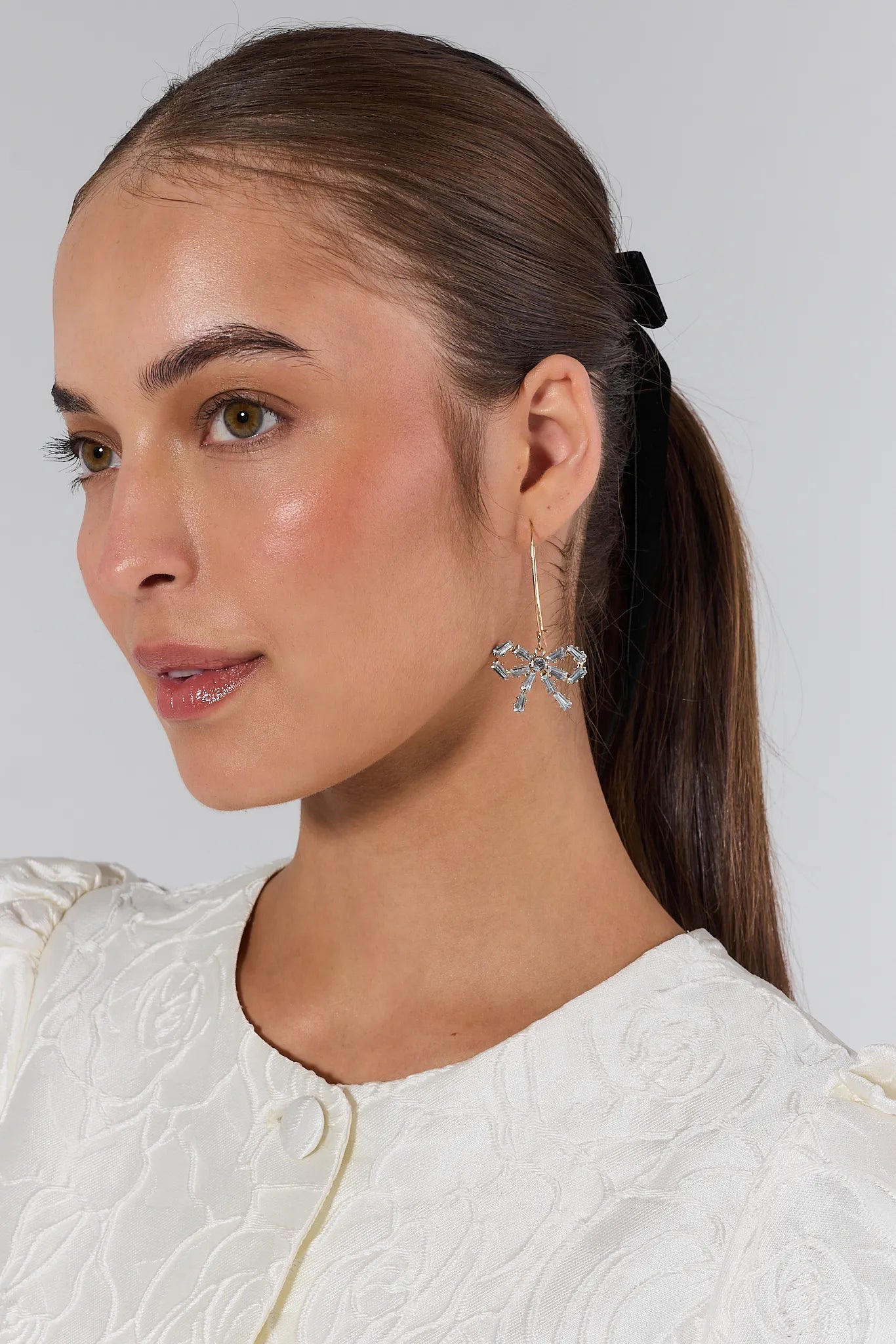 Woman wearing silver earrings with a plain background