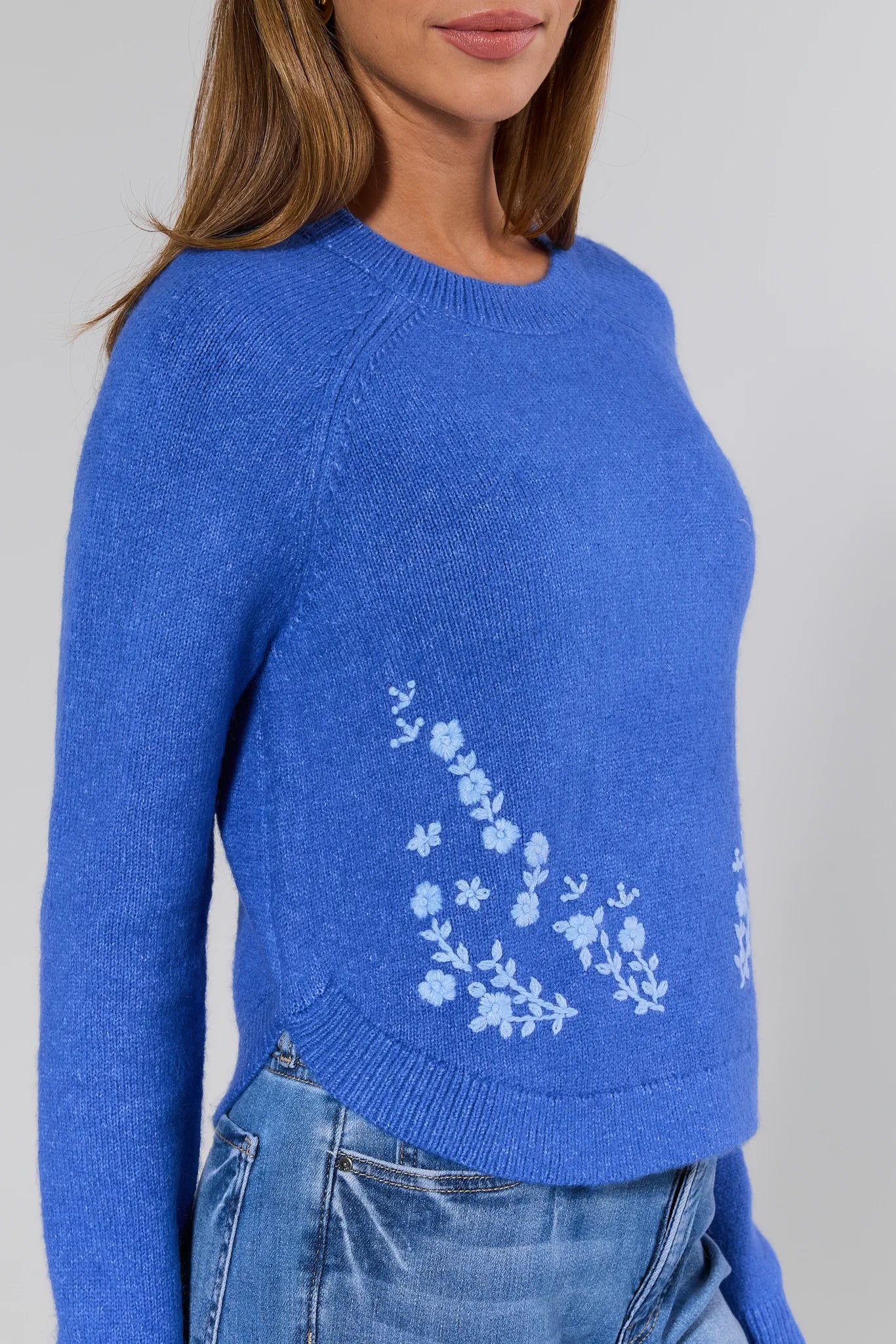 Blue sweater with floral design on a plain background