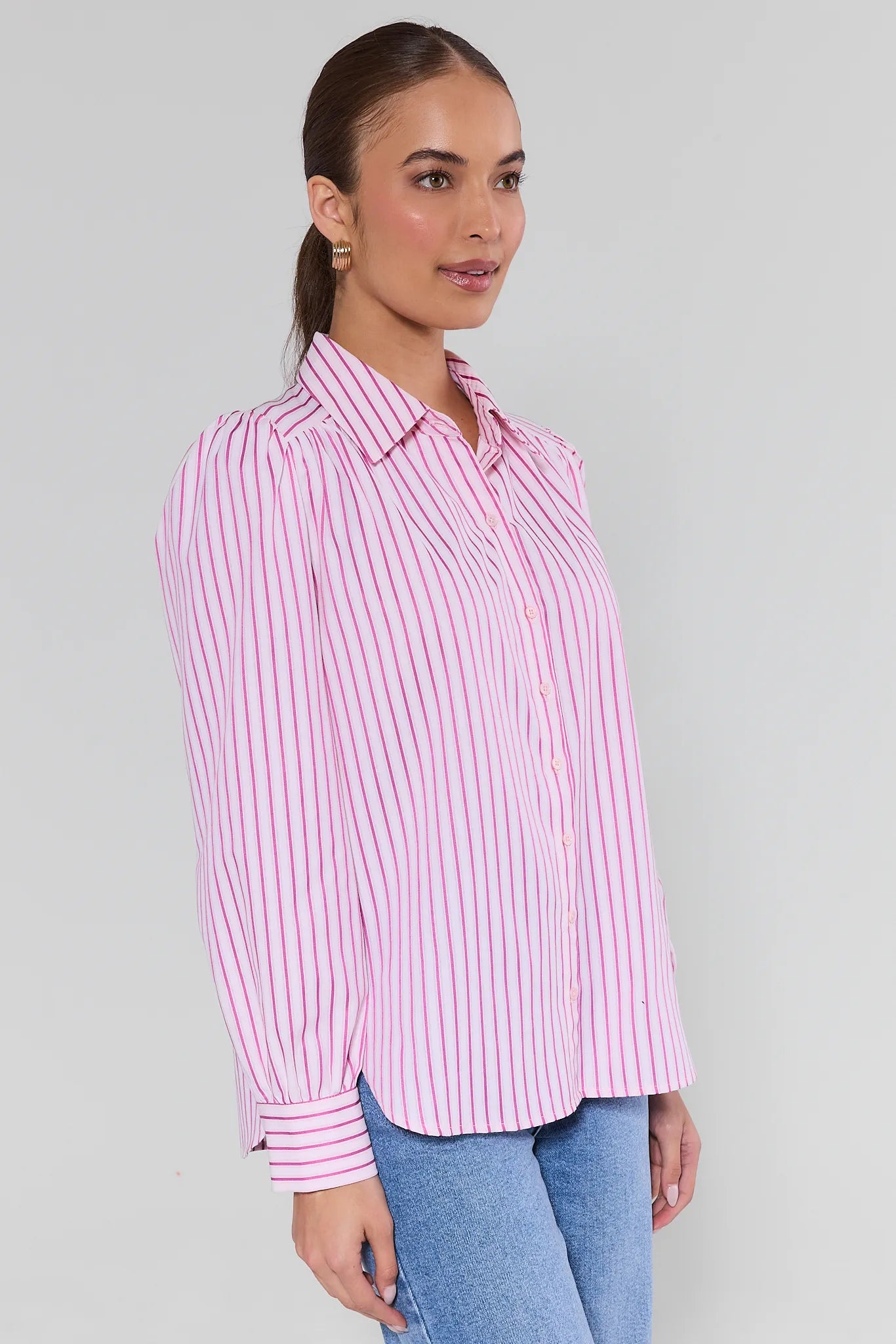 Woman wearing a pink and white striped shirt against a gray background