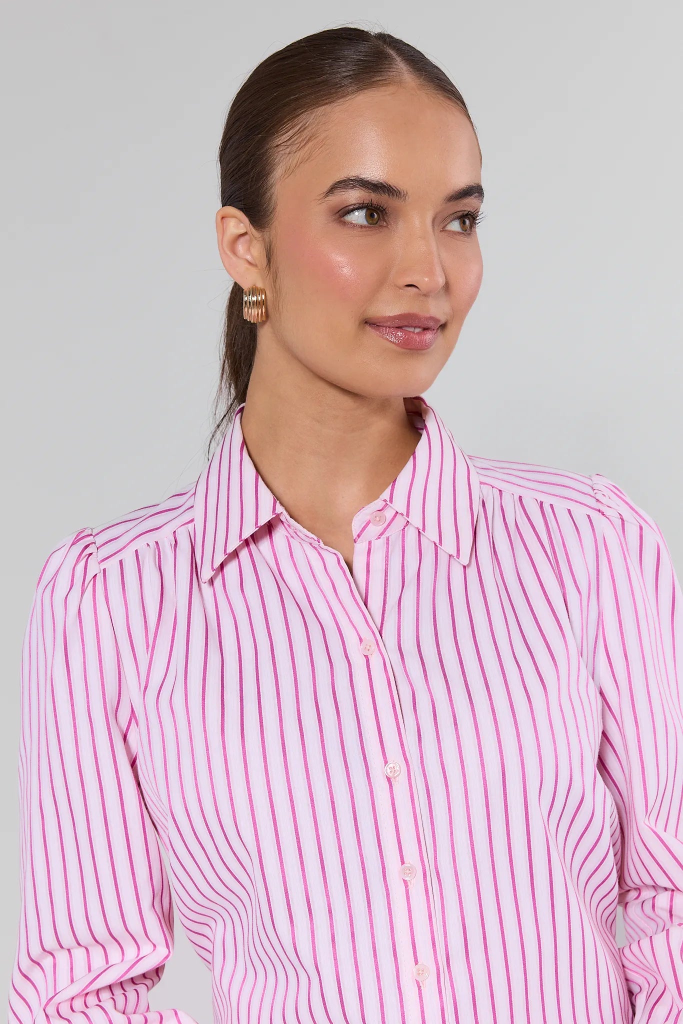 Woman wearing a pink striped shirt against a plain background