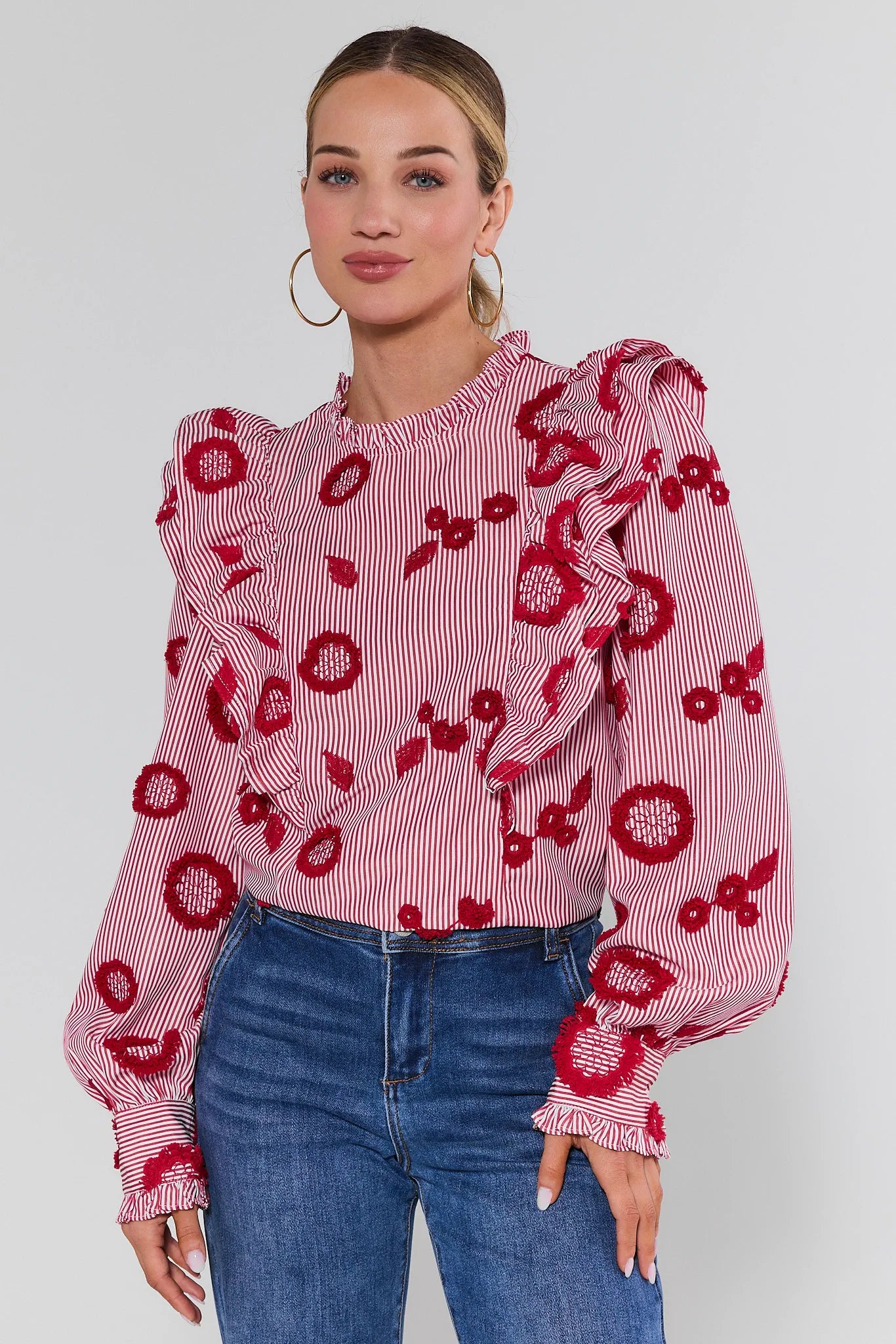 Woman wearing a red floral blouse with blue jeans on a white background