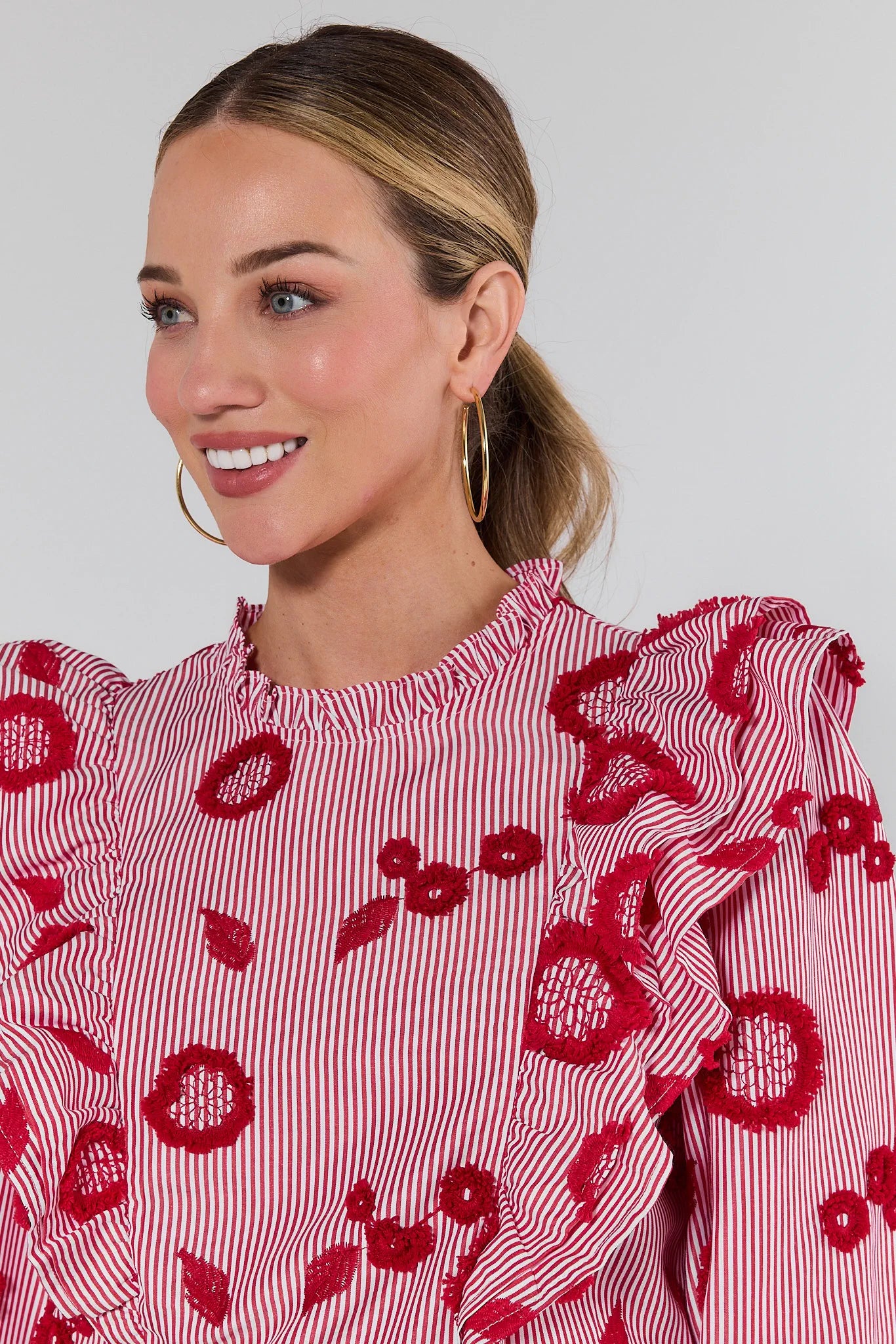 Woman wearing a red and white patterned blouse against a plain background