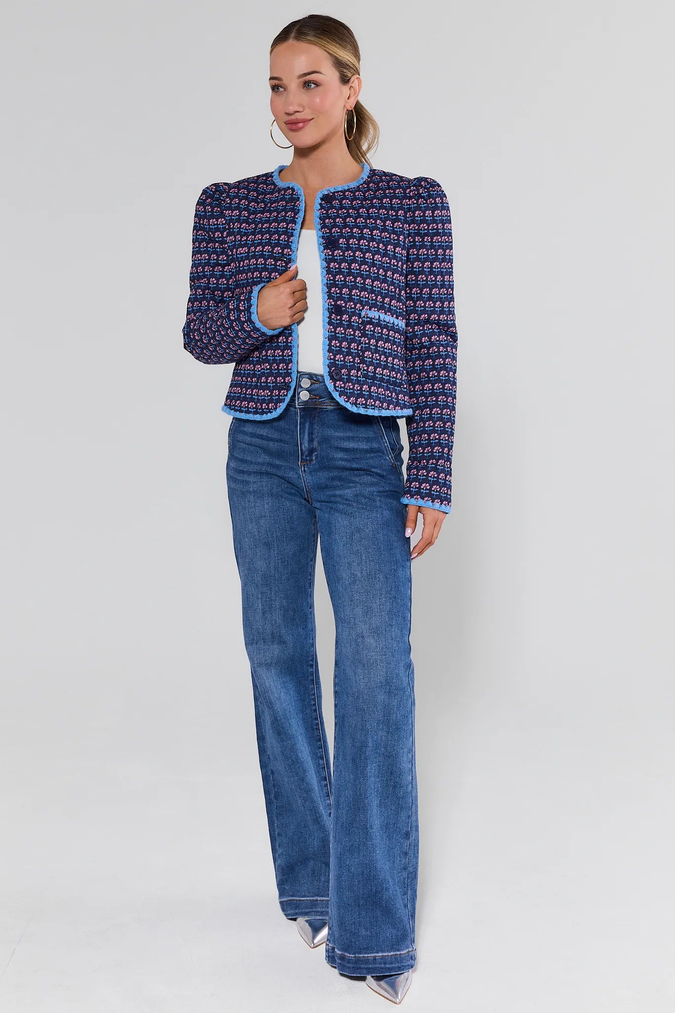 Woman wearing a patterned jacket and blue jeans on a white background